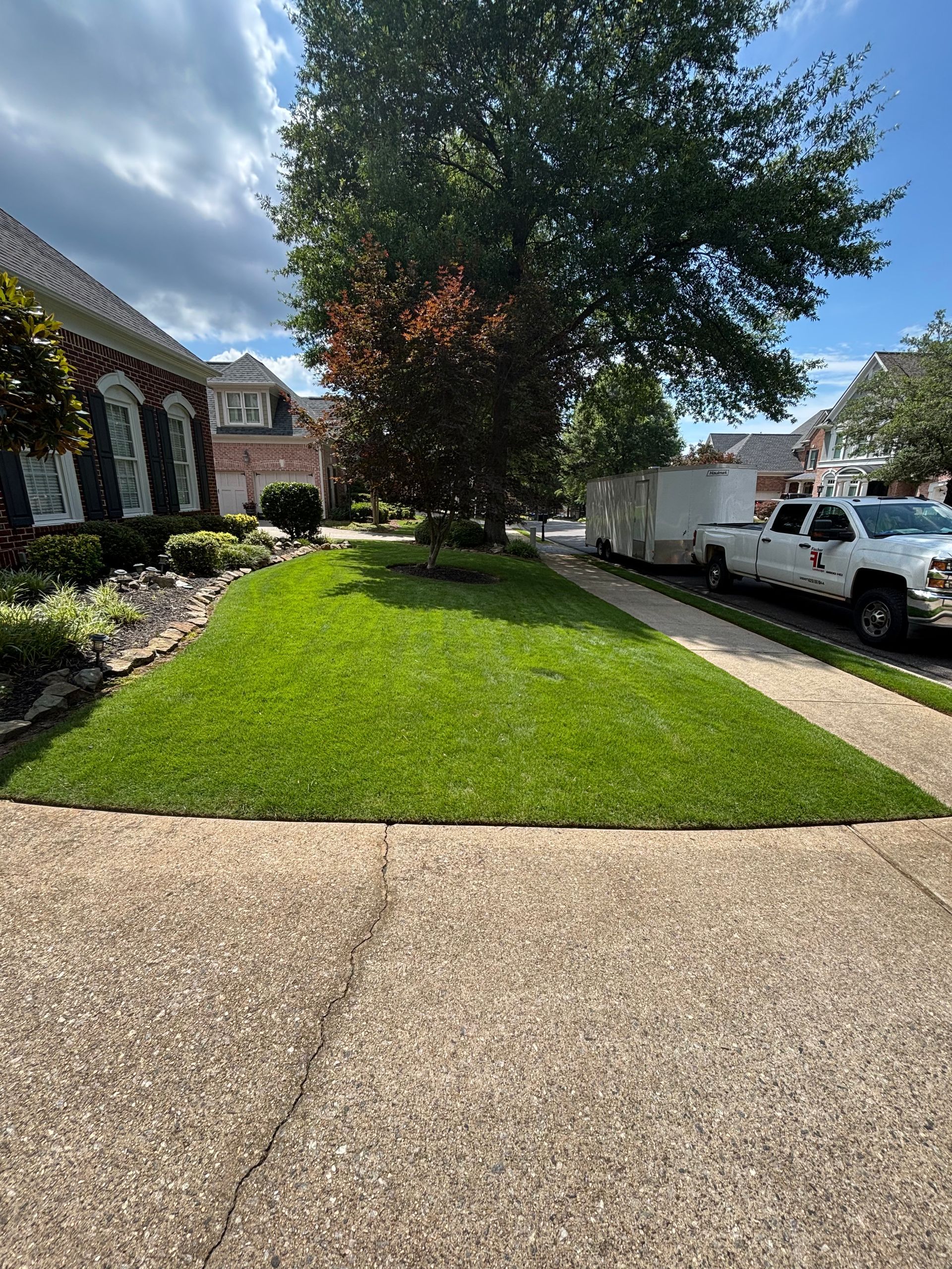 A lush green lawn with a white truck parked in front of a house.
