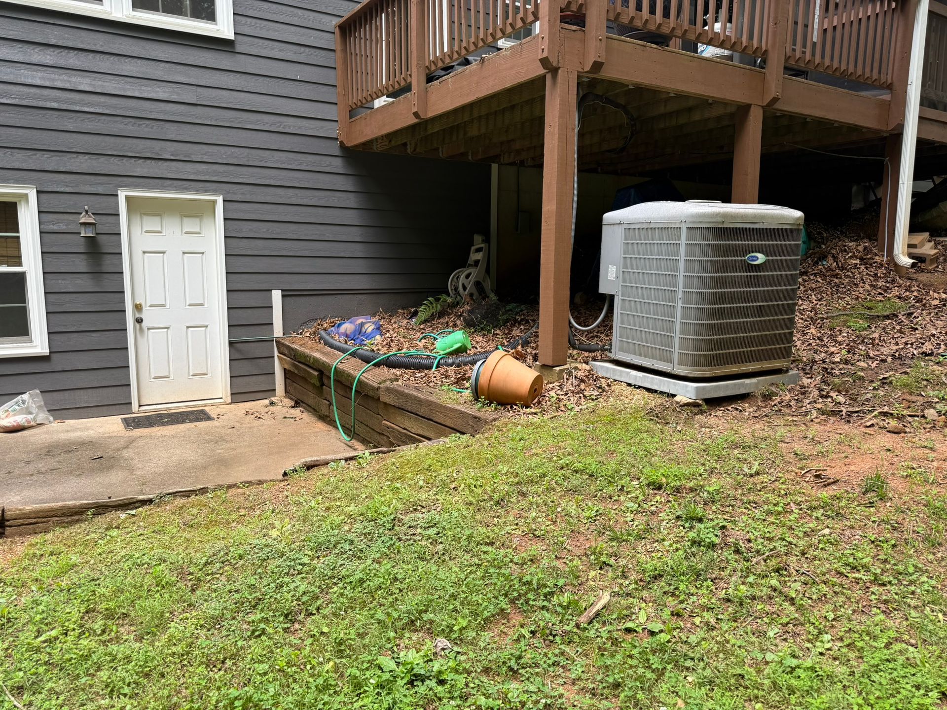 A house with a deck and an air conditioner in the backyard.