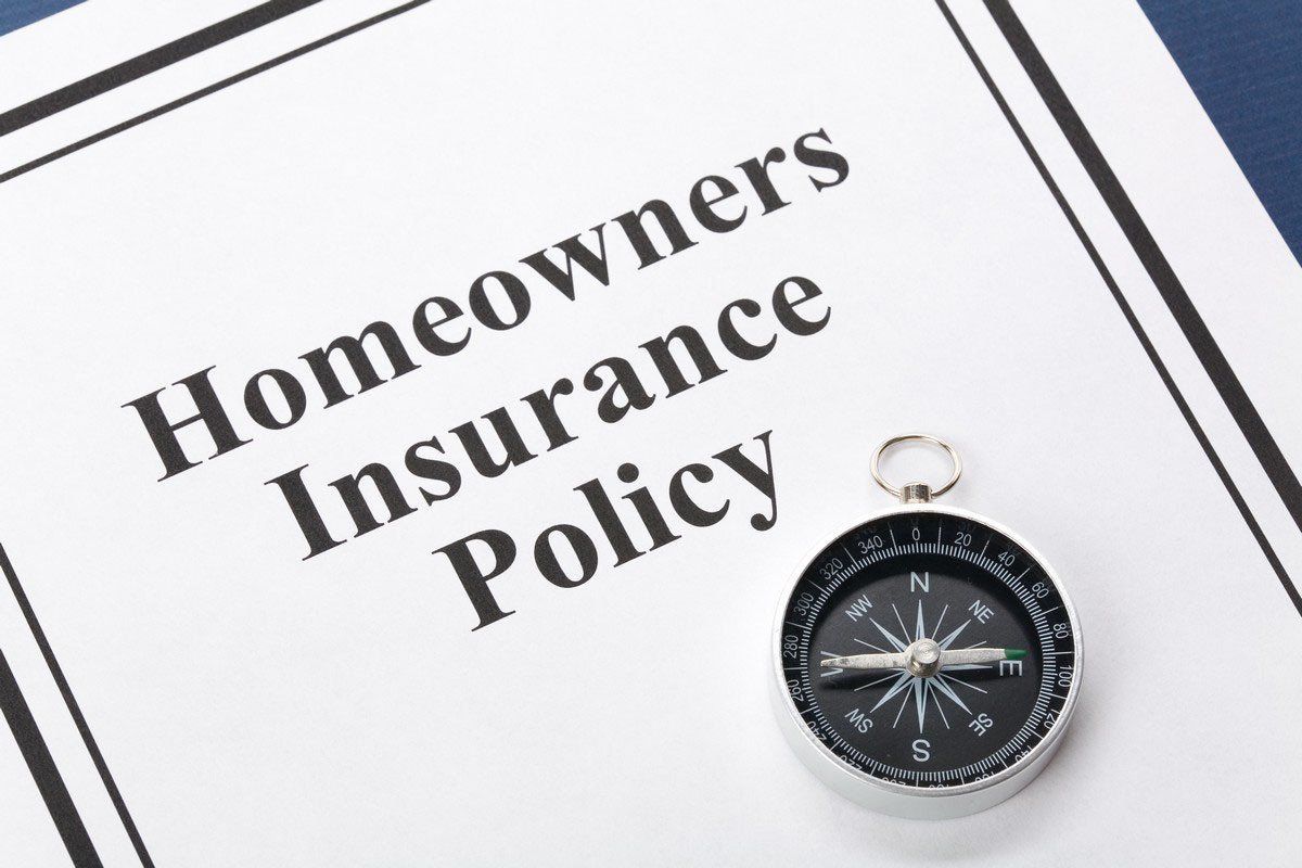 Homeowners Insurance Policy document with a compass resting on it.