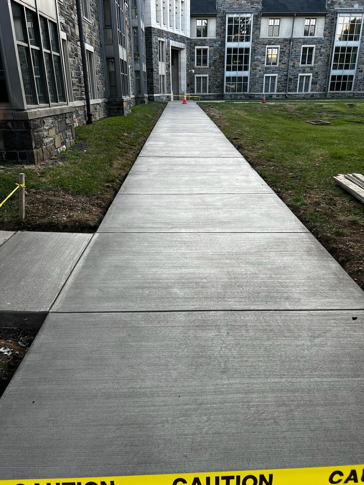 a concrete walkway leading to a building with a yellow caution tape