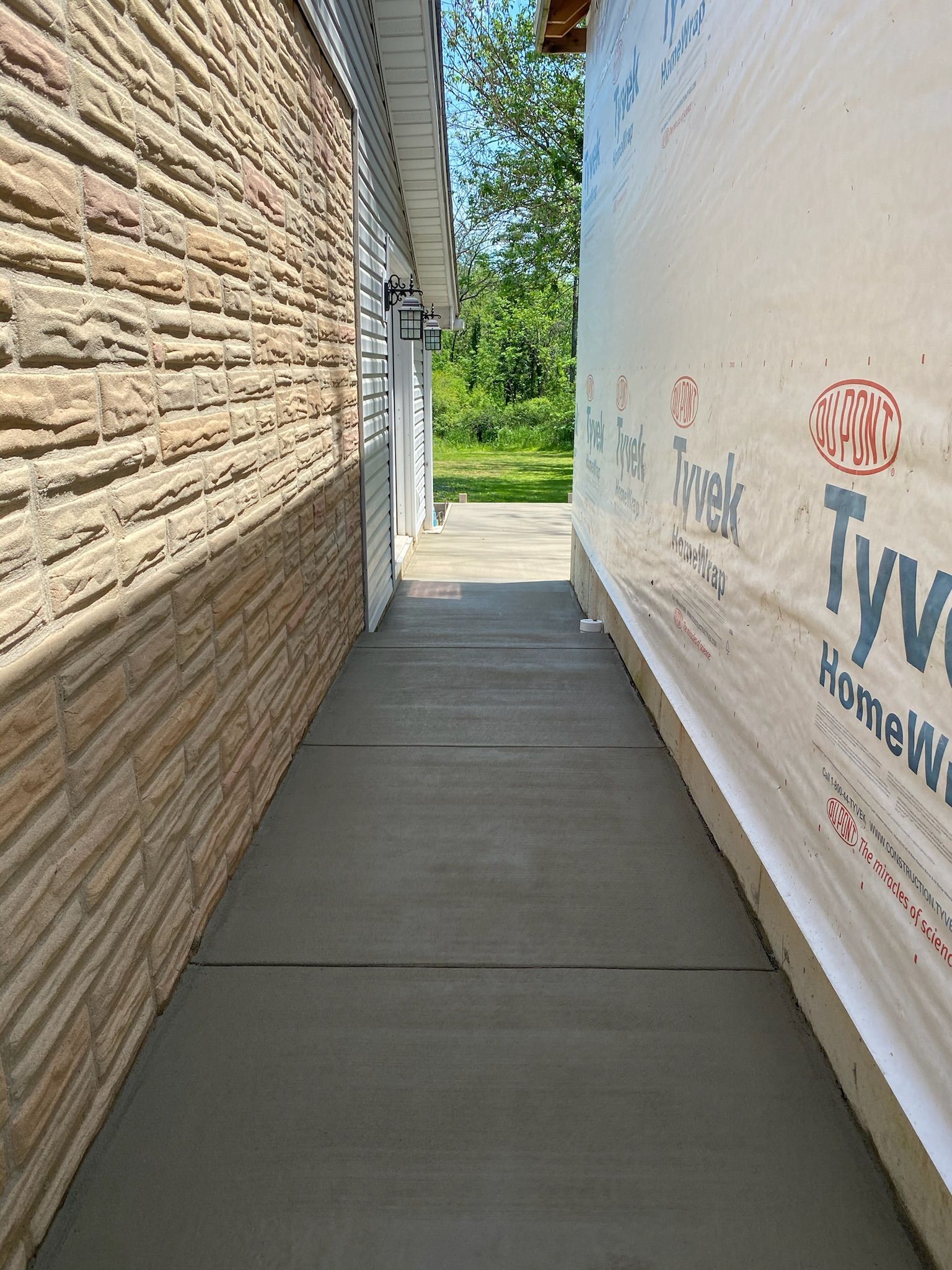 a walkway between two buildings with a brick wall and a white wall