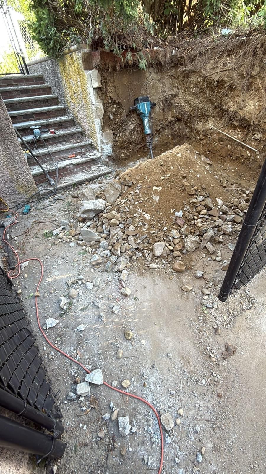 Construction site with stairs and an excavator, rocks on the ground.