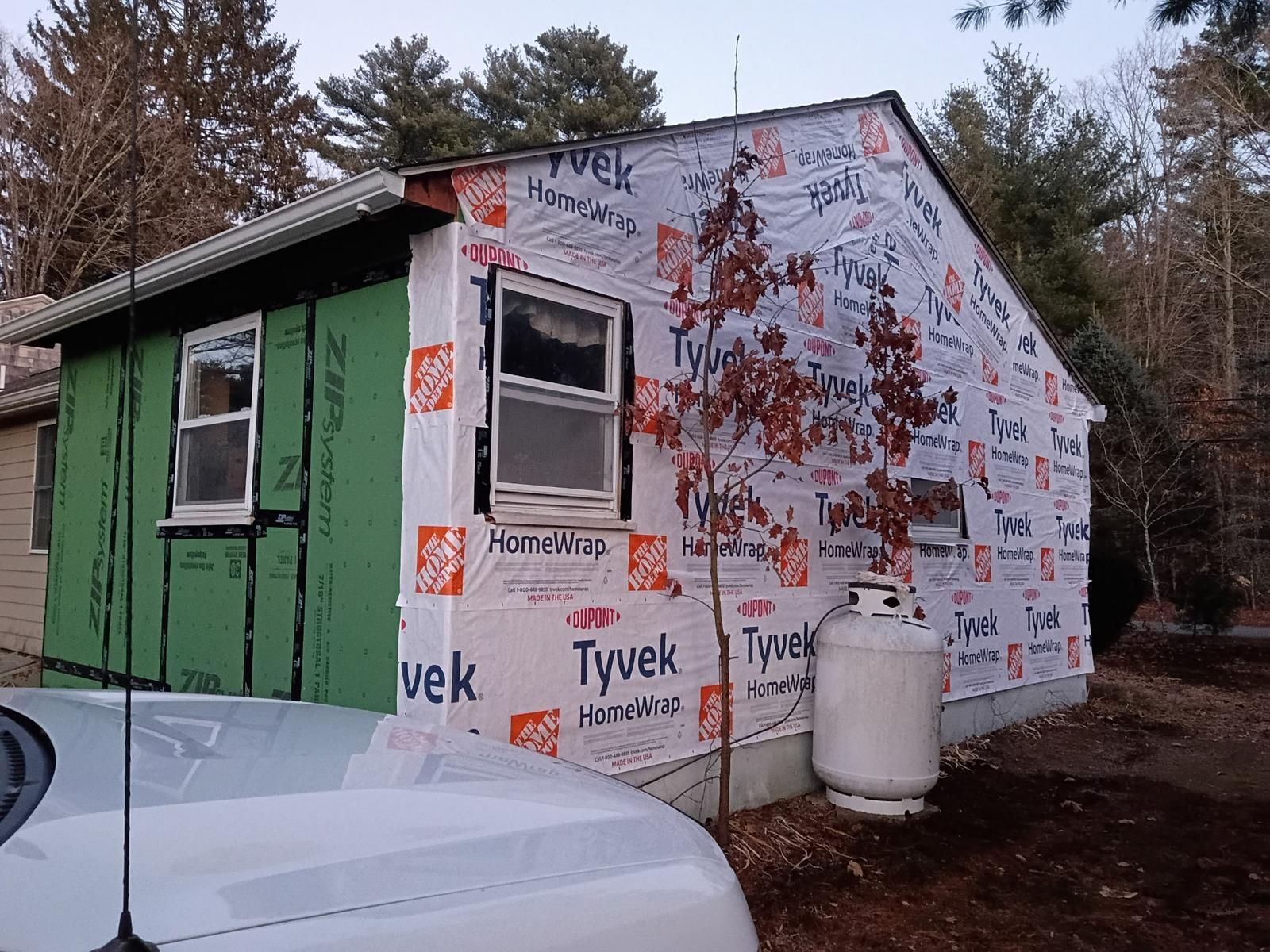 Exterior of a small building under construction, wrapped in Tyvek.  Propane tank visible.