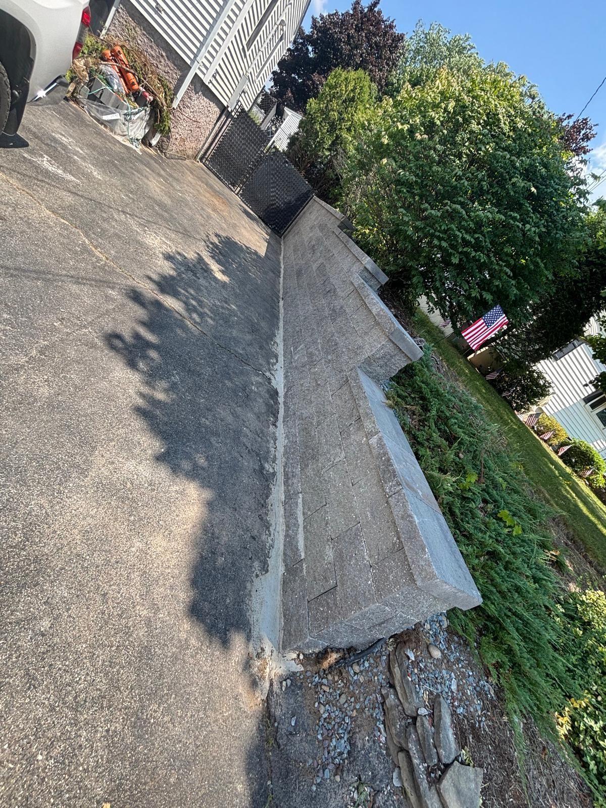 Concrete retaining wall alongside an asphalt driveway and a grassy embankment.