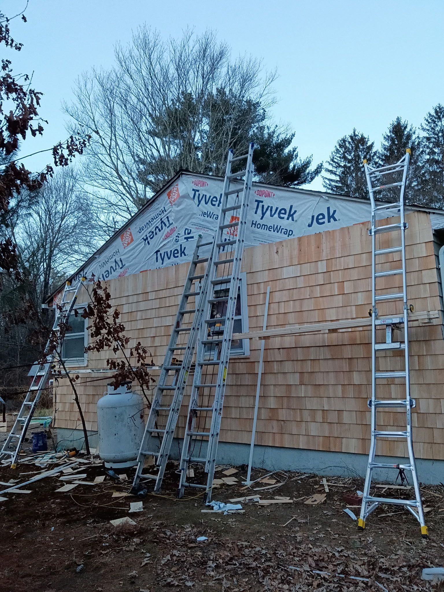 House exterior under construction, with ladders and cedar shingles.