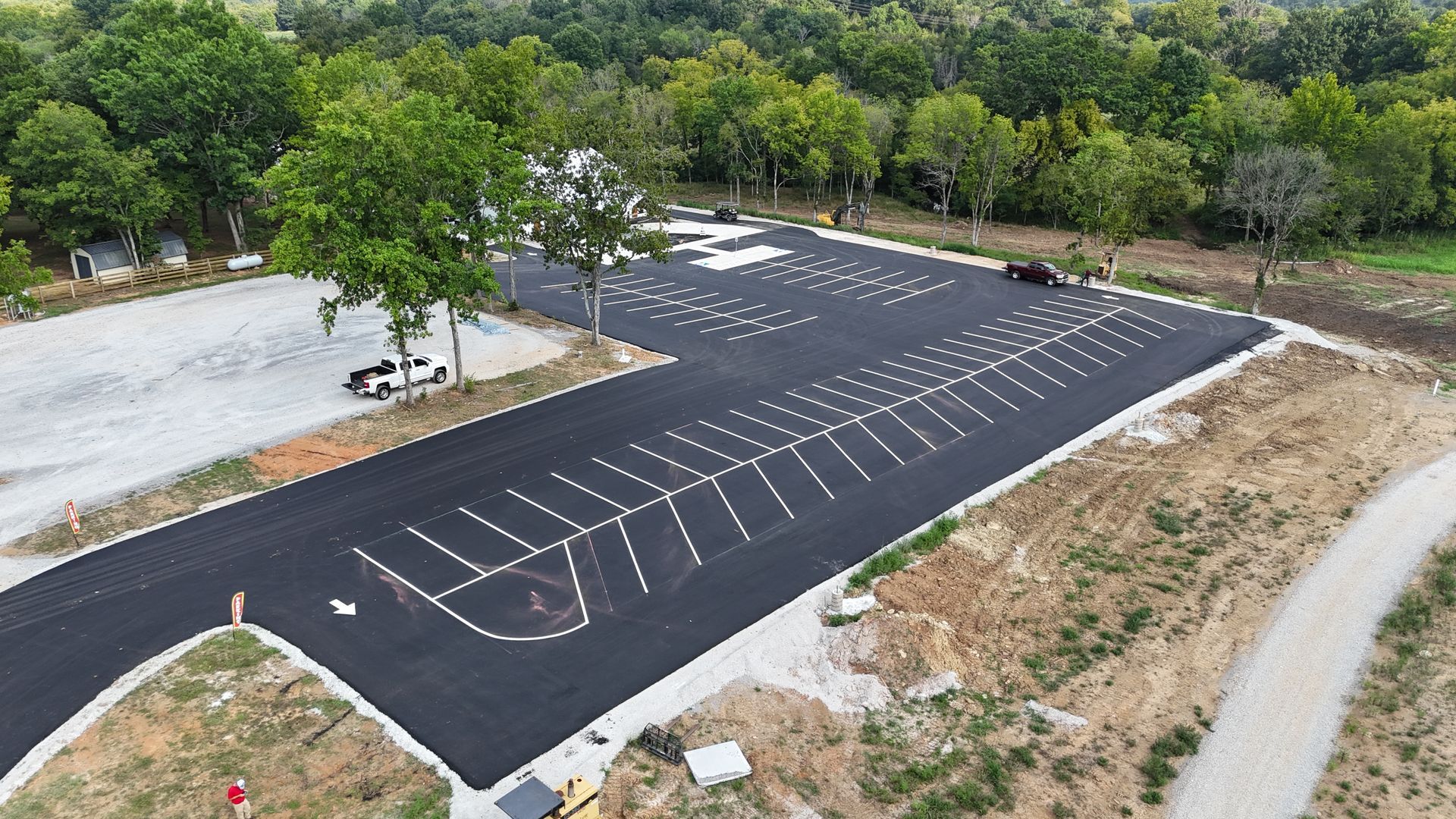 An aerial view of a parking lot with trees in the background.