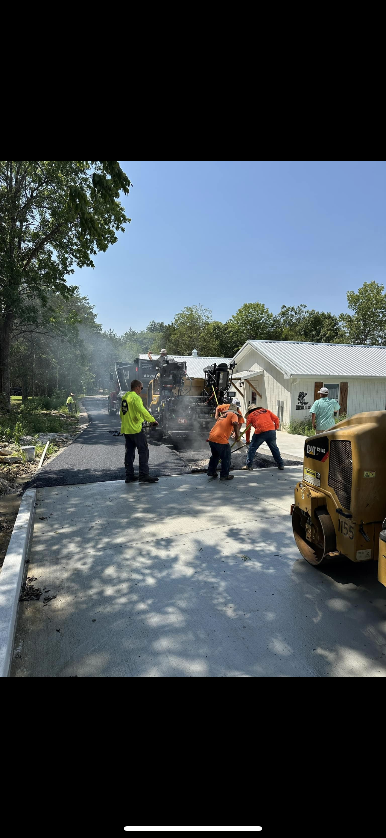 A group of people are working on a road in front of a house.