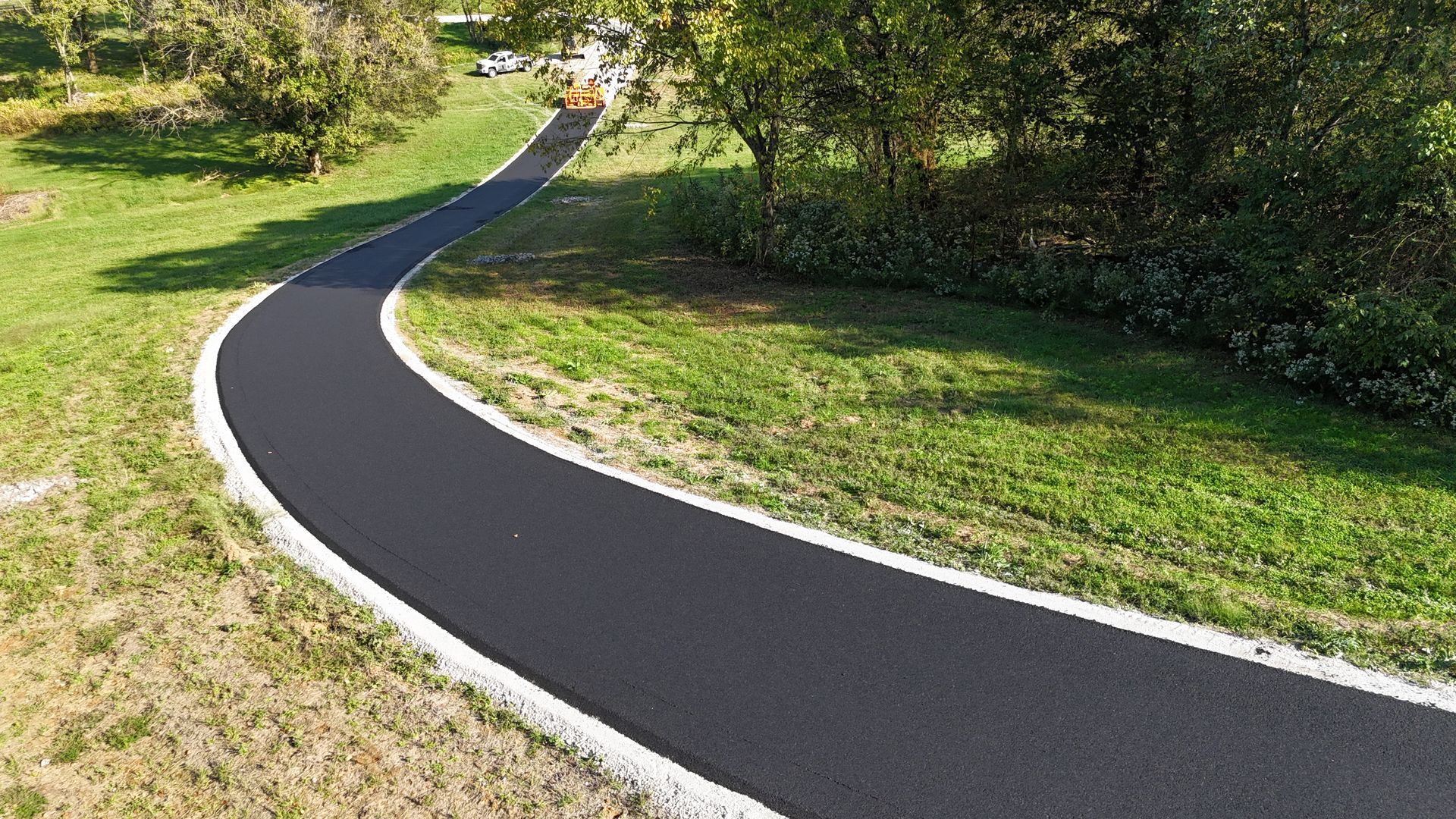 A curvy road going through a grassy field.