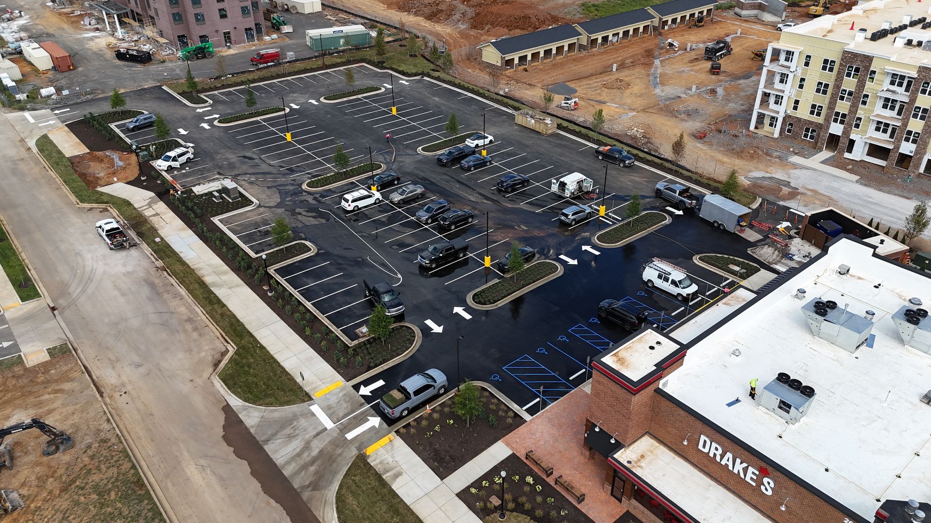 An aerial view of a parking lot with a building in the background.