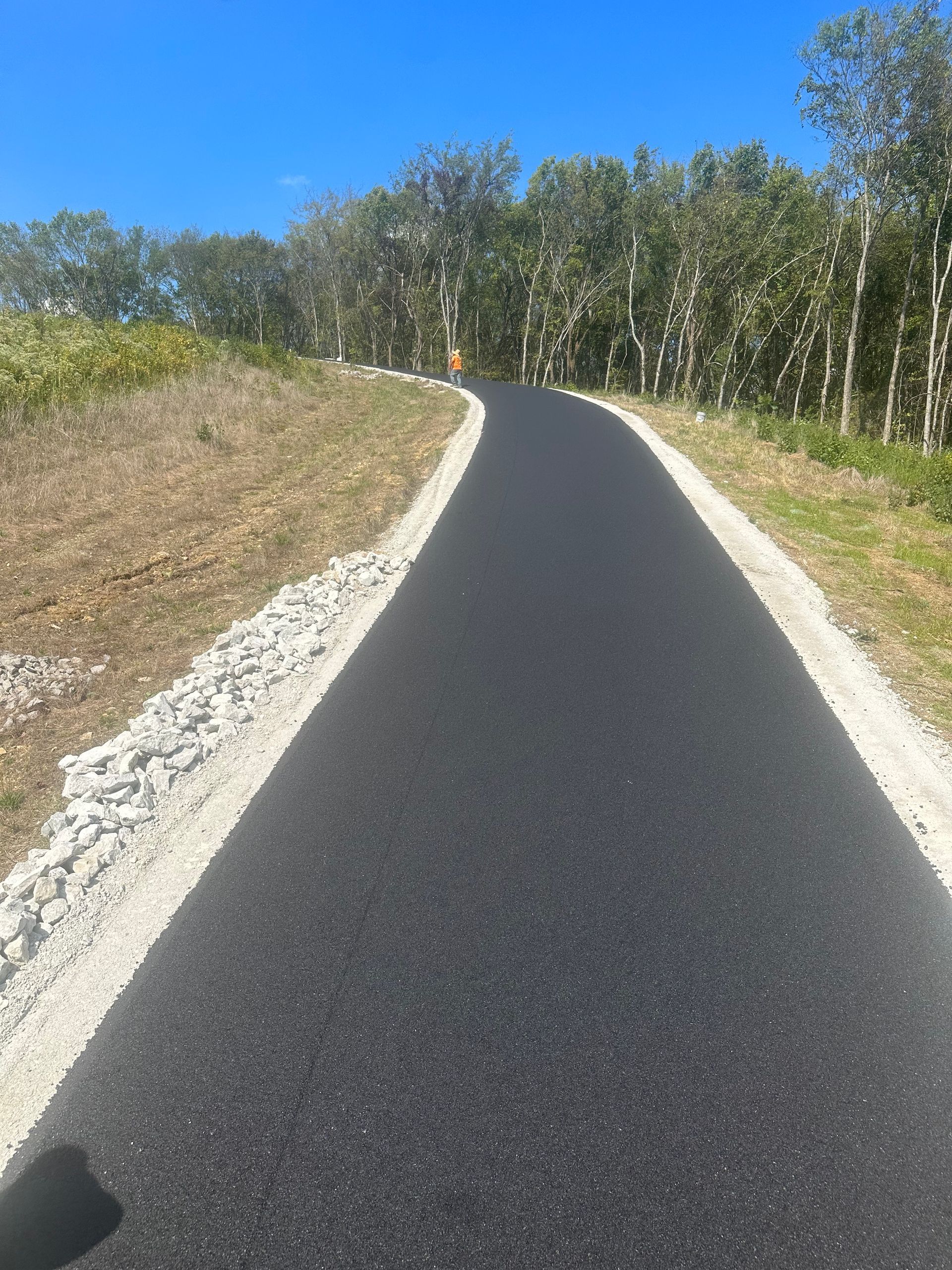 A black road with trees on the side of it
