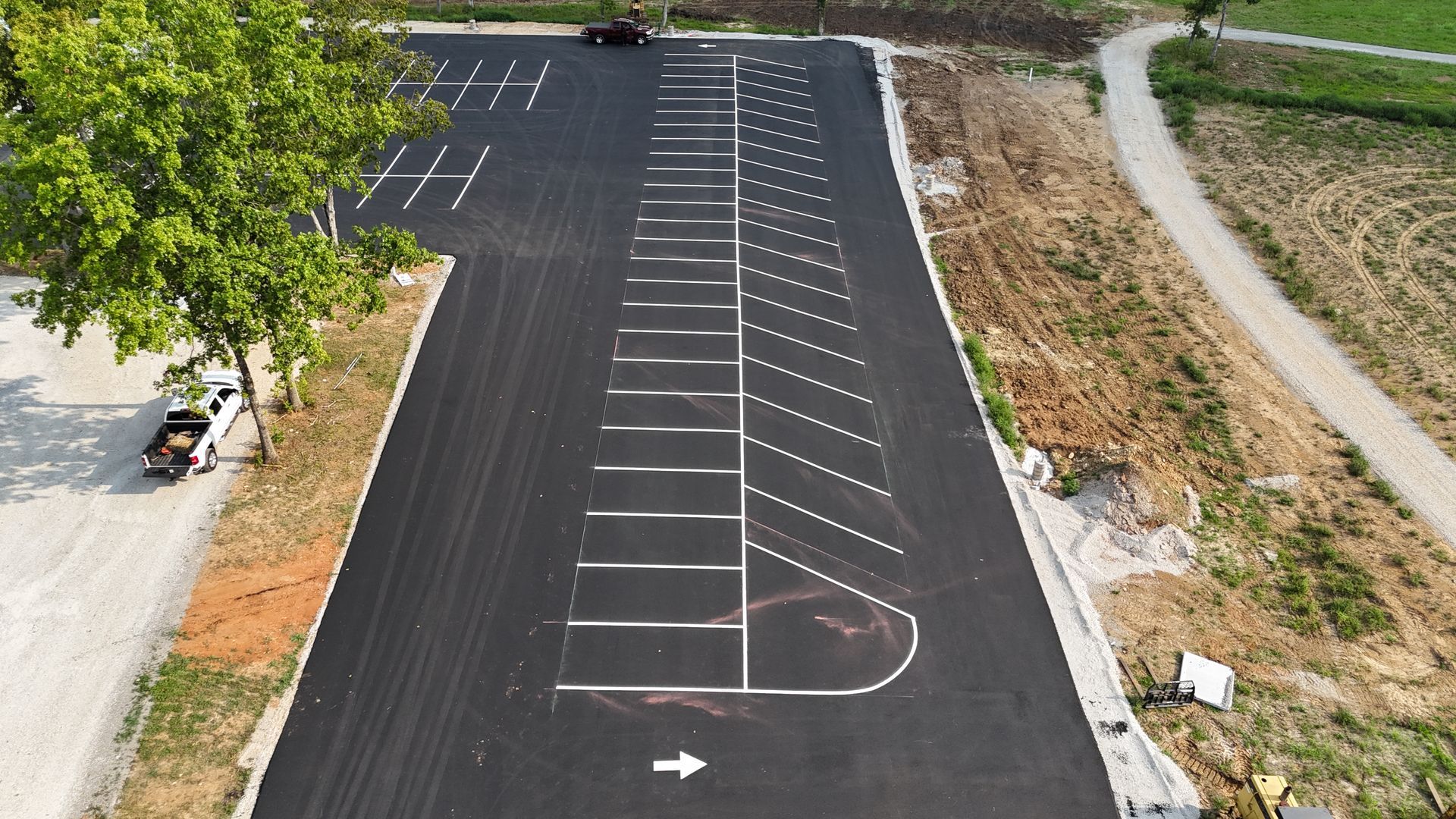 An aerial view of a parking lot with a white arrow pointing to the right.