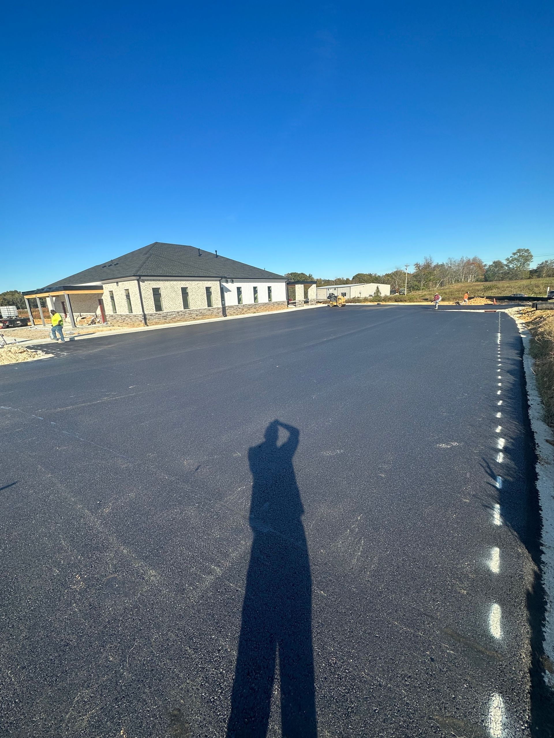 A person is taking a picture of their shadow on the road.