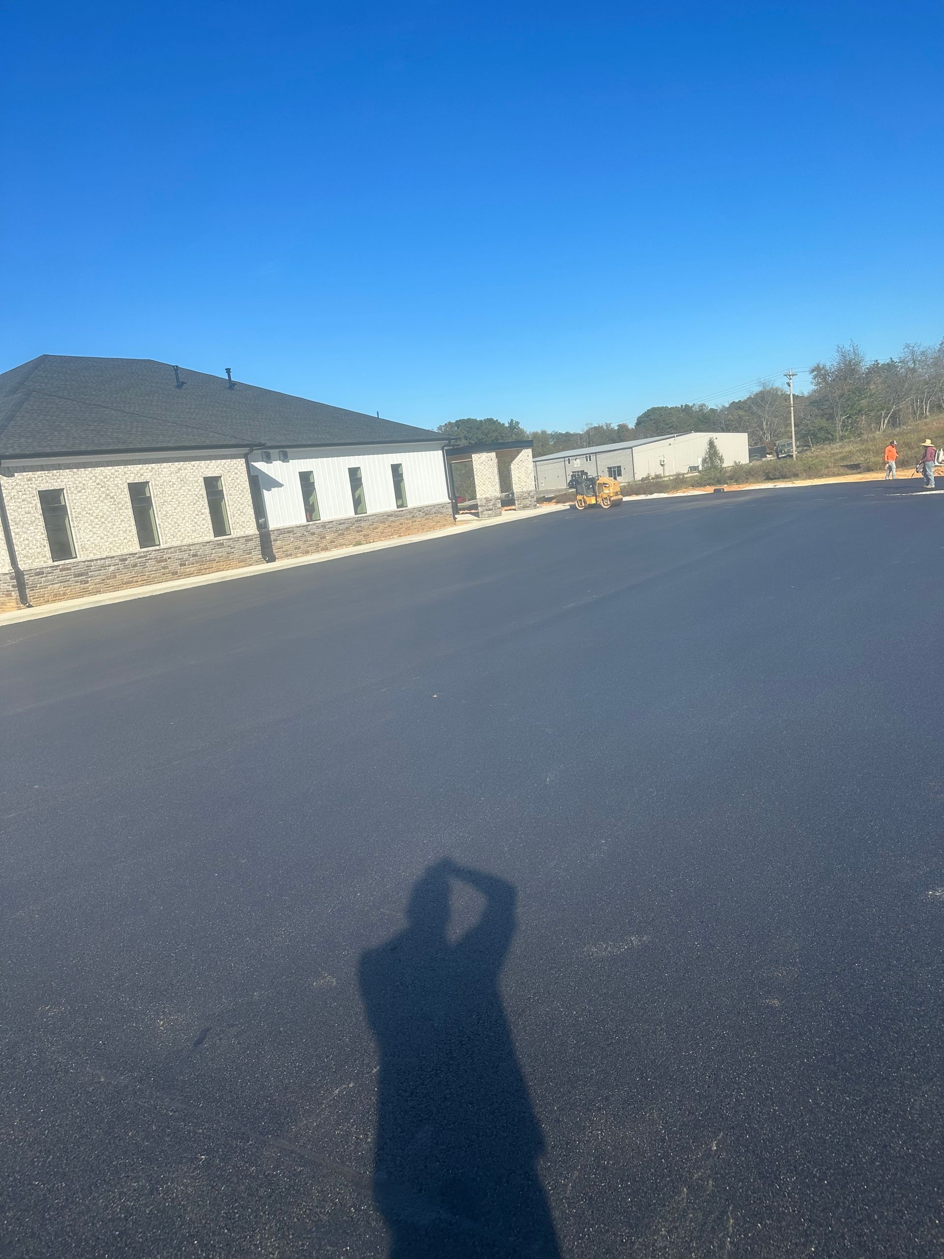 A person is taking a picture of a parking lot with a building in the background.