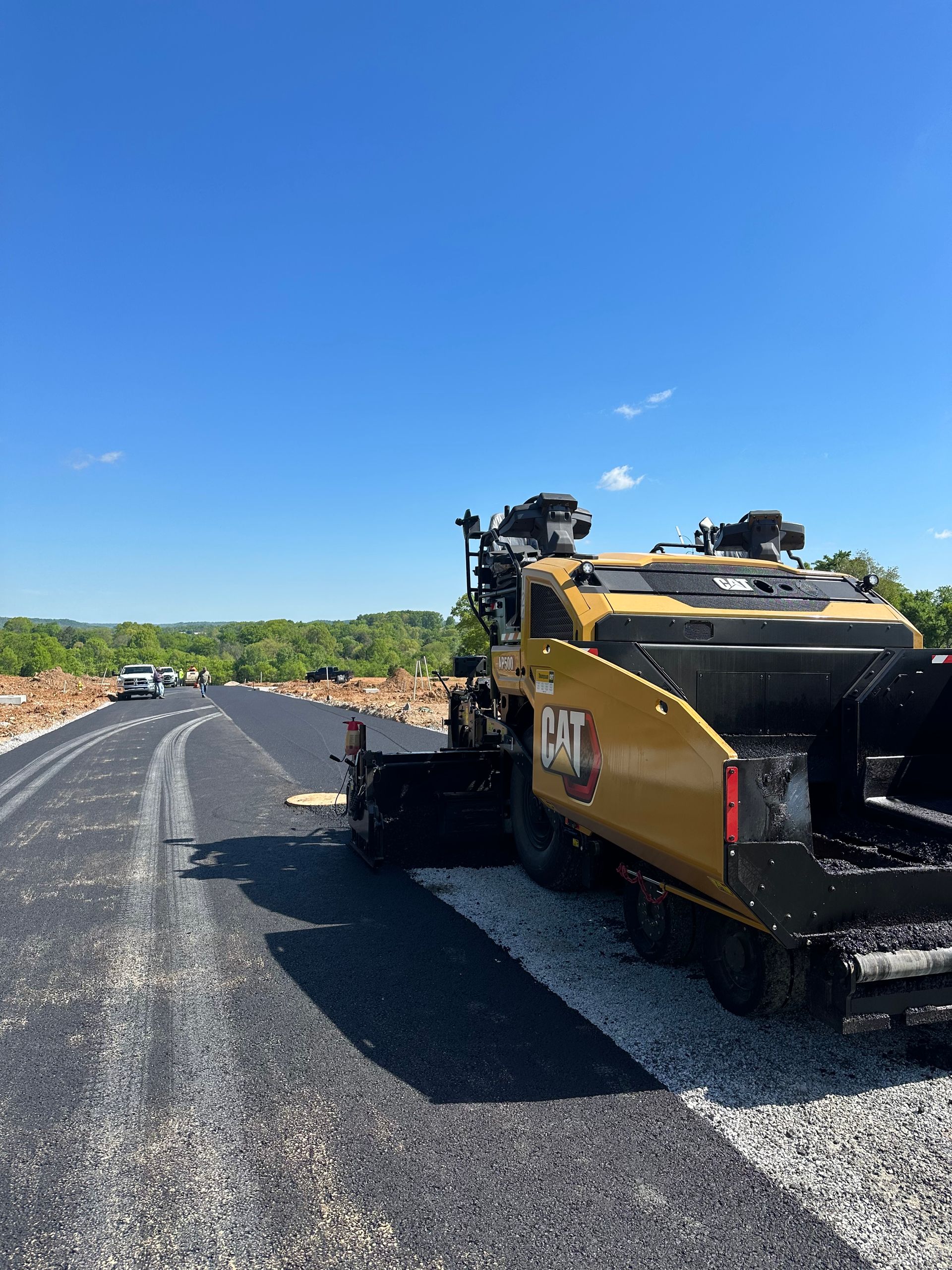 A cat asphalt paving machine is sitting on the side of a road.