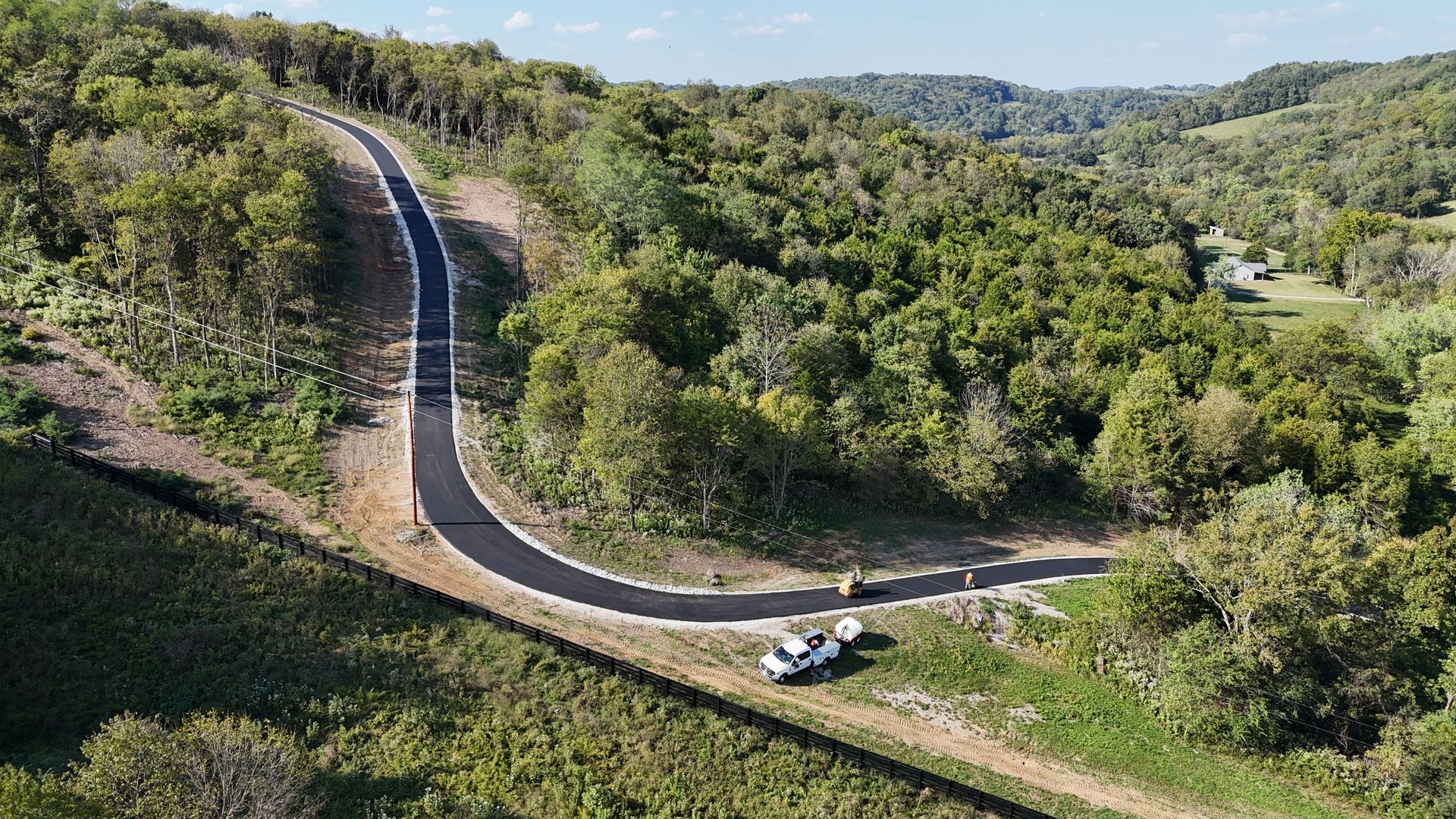An aerial view of a curvy road surrounded by trees.