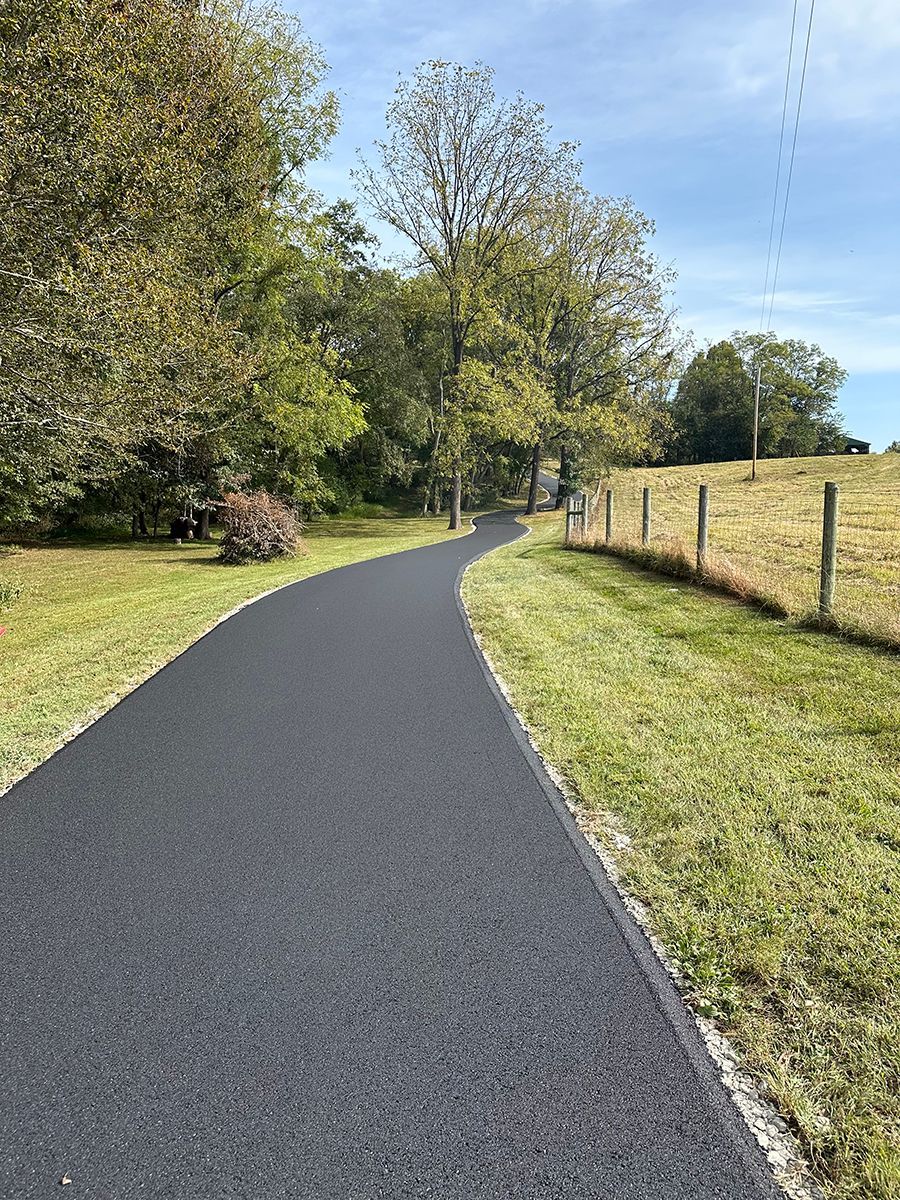 a paved path going through a grassy field