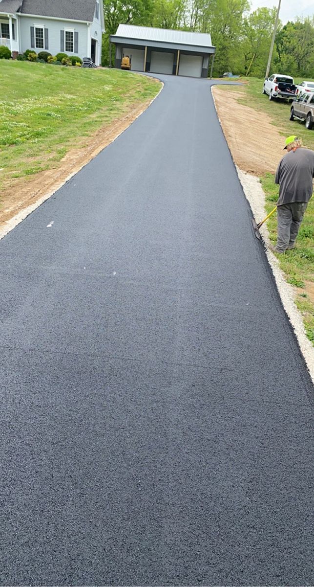 a man is walking down a newly paved driveway in front of a house .