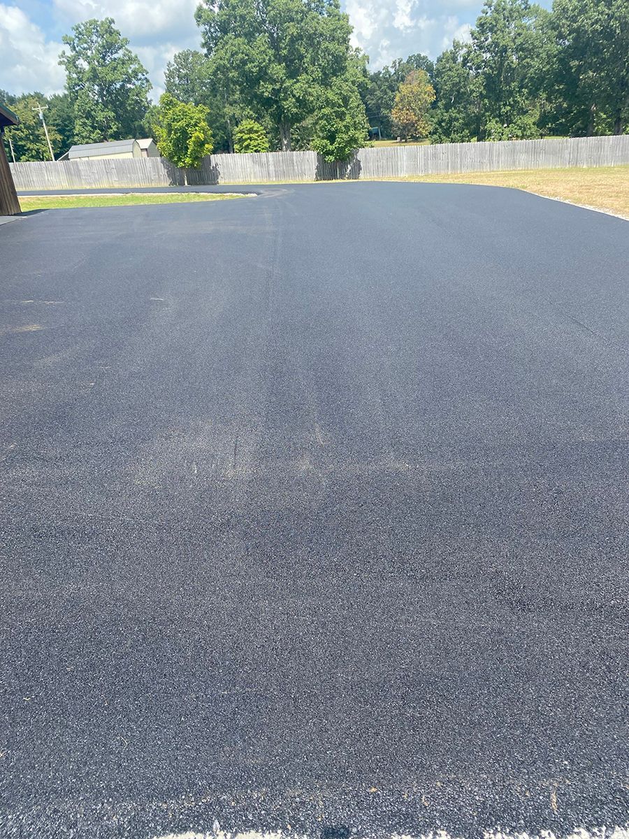a black asphalt driveway with trees in the background