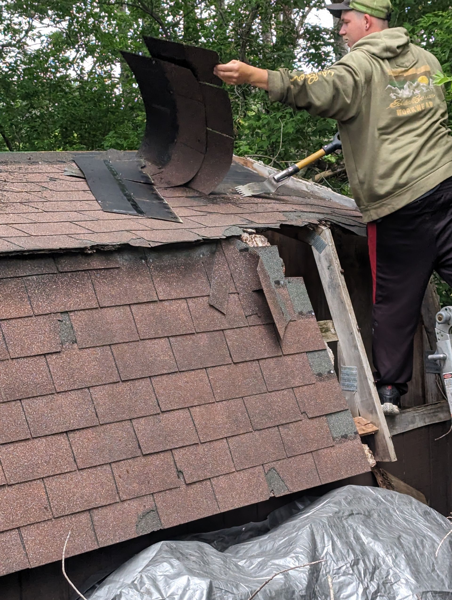 A man is working on a roof with a hammer.