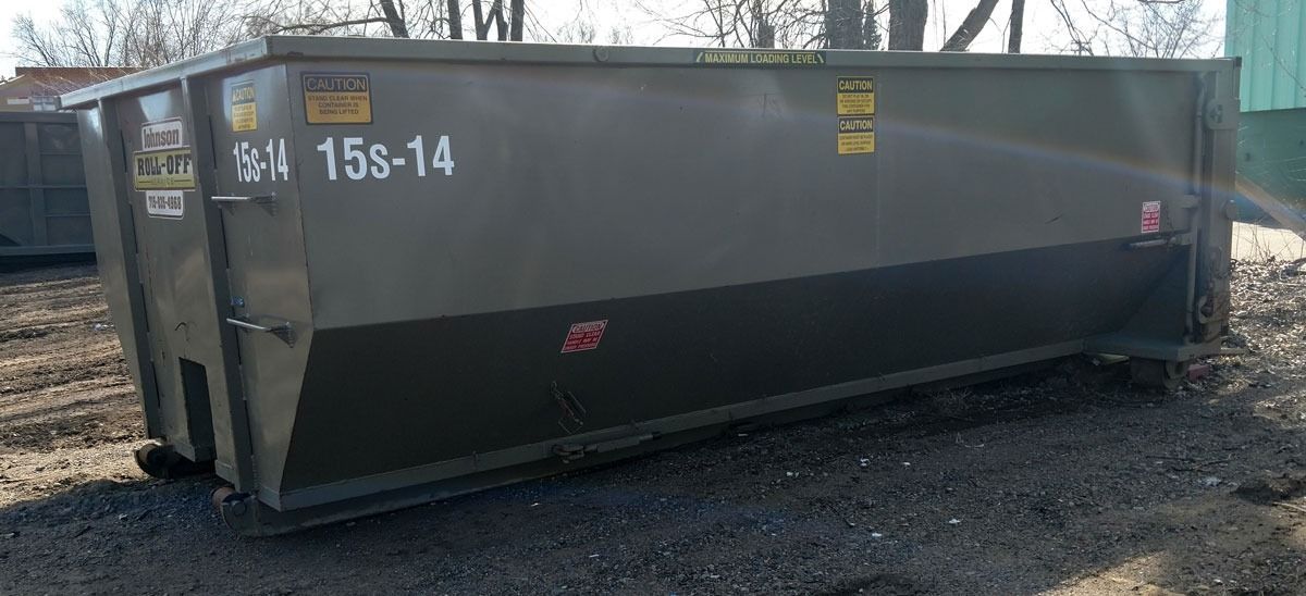 A large, dark green dumpster labeled 