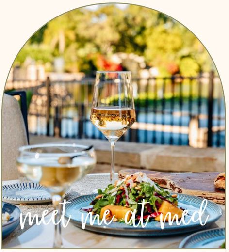 Wine glass on a table with a plated meal.
