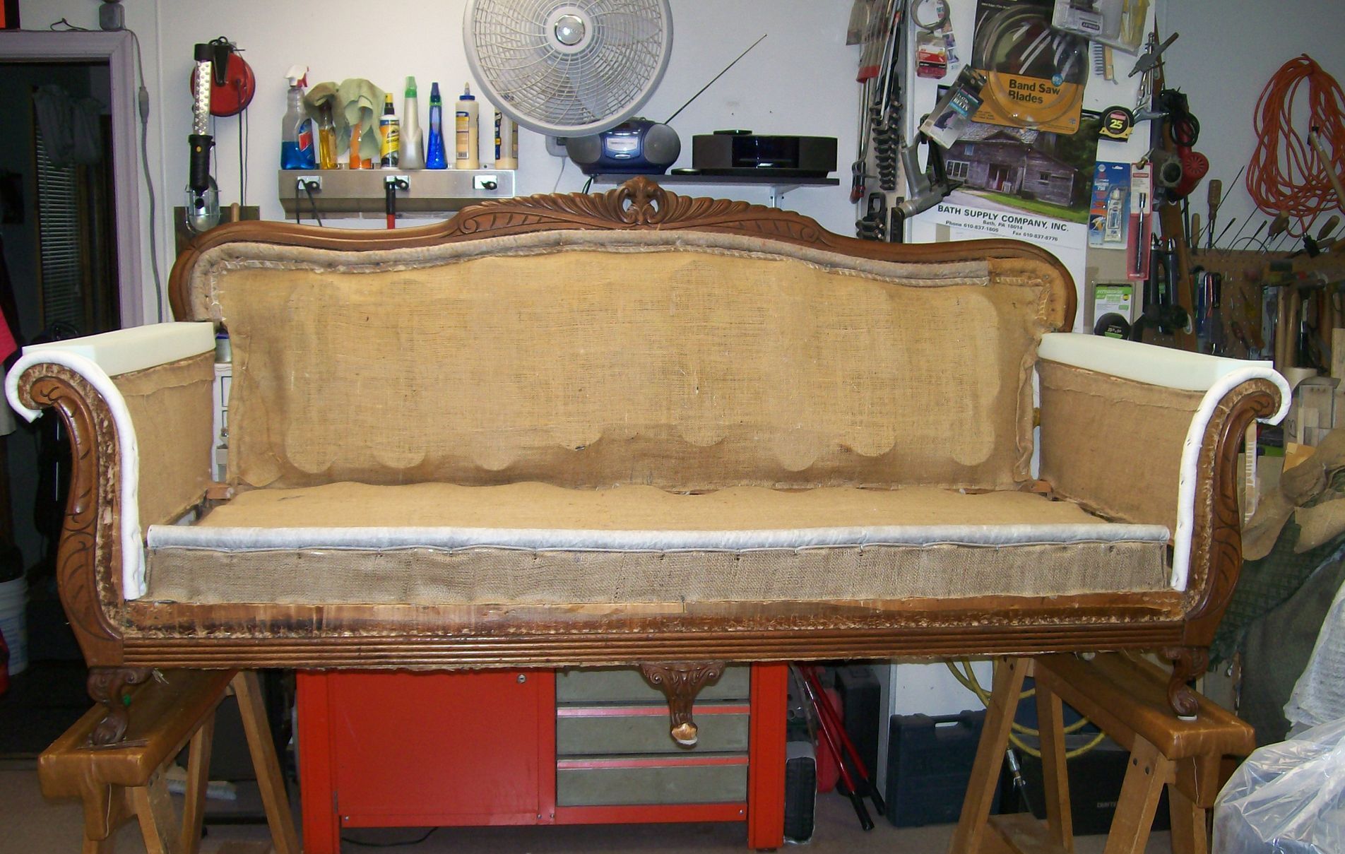 A couch is being remodeled in a room with a fan on the wall
