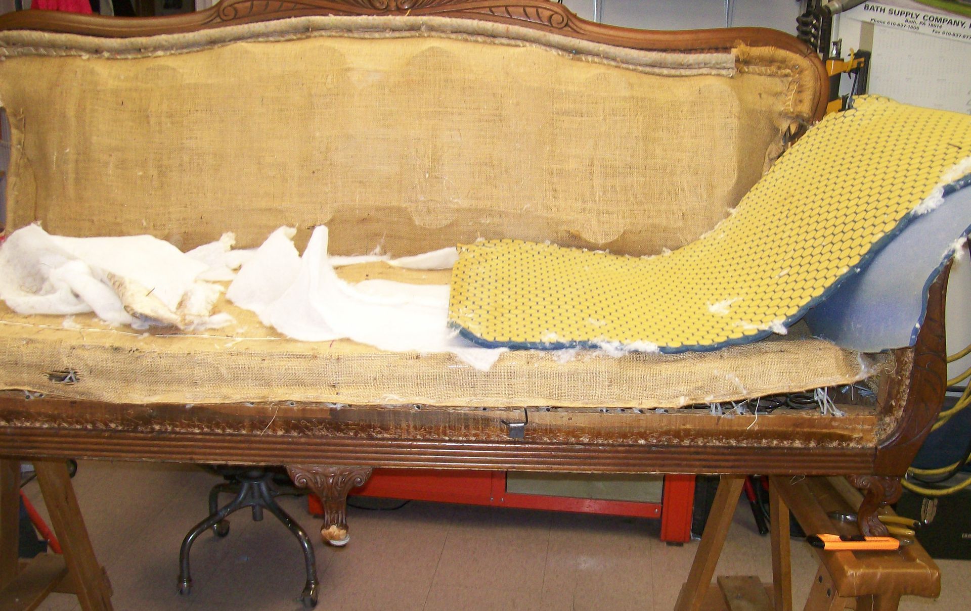 A couch with a yellow cushion is sitting on a wooden table.