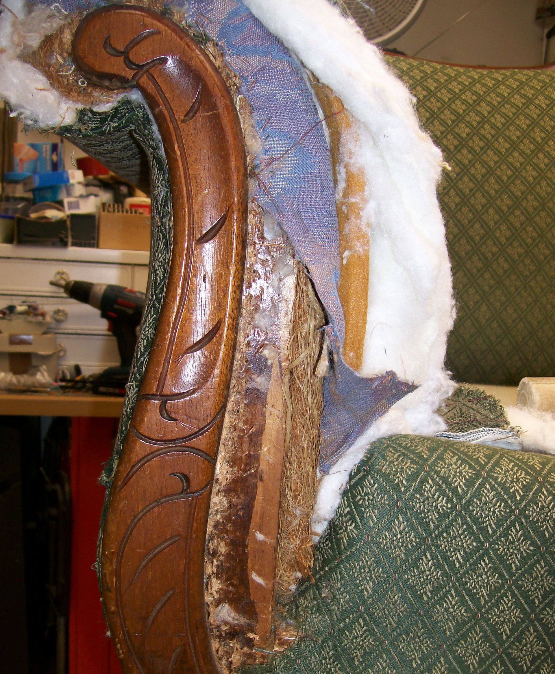 A chair with a wooden arm rest is being repaired