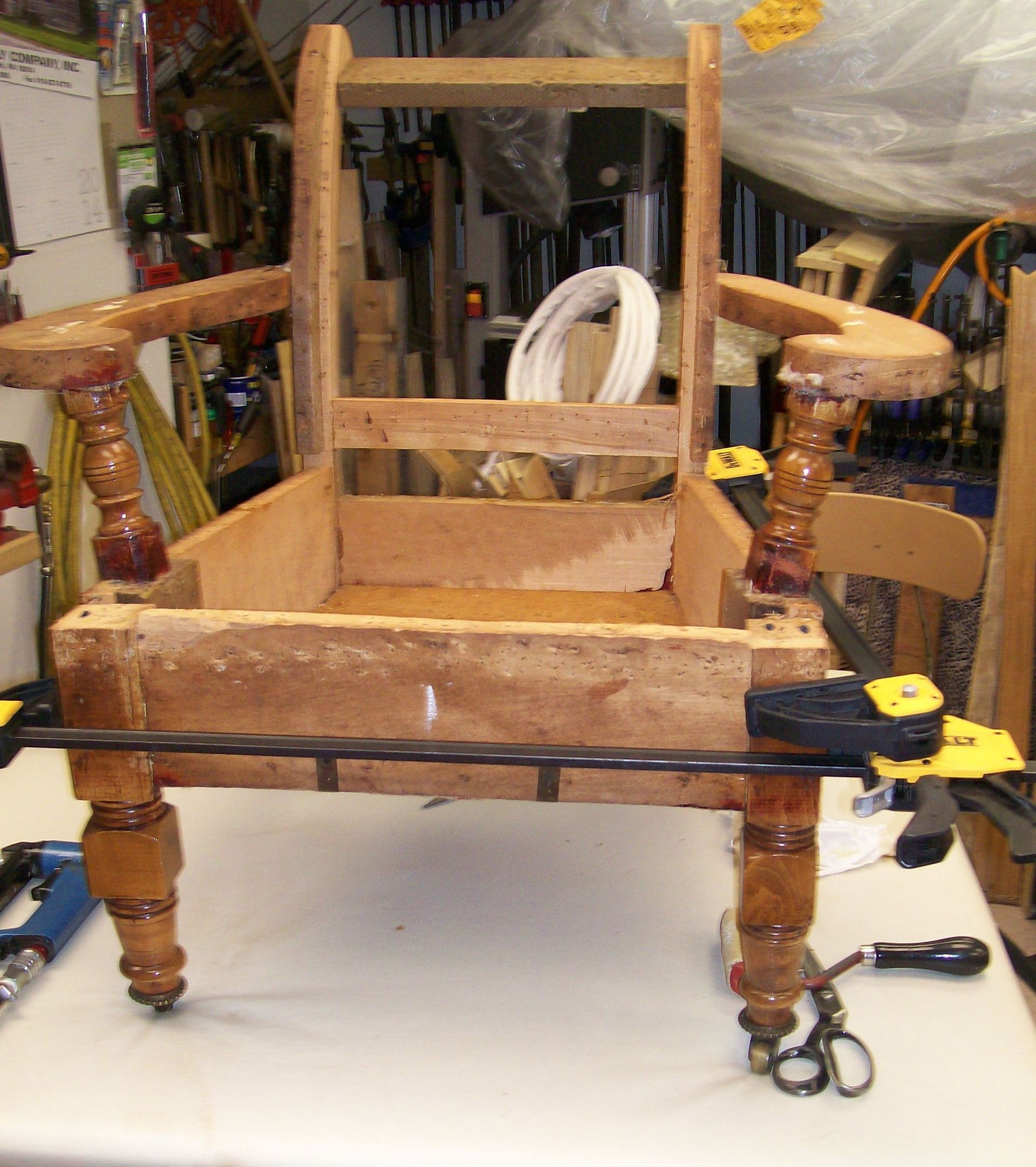 A wooden chair is being glued together with clamps