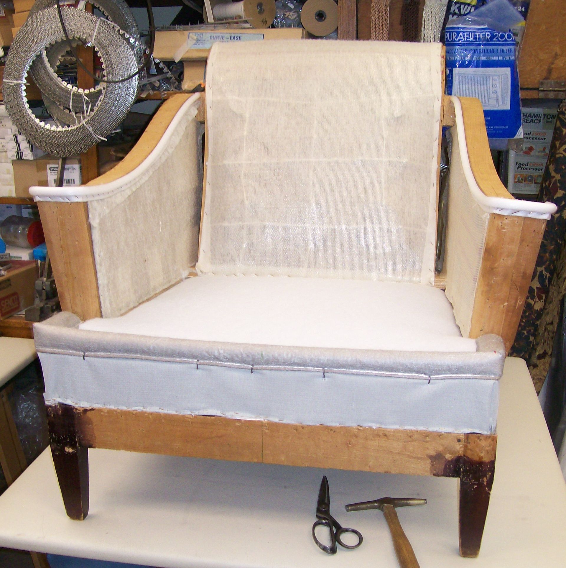 A chair is sitting on a table next to a pair of scissors and a hammer