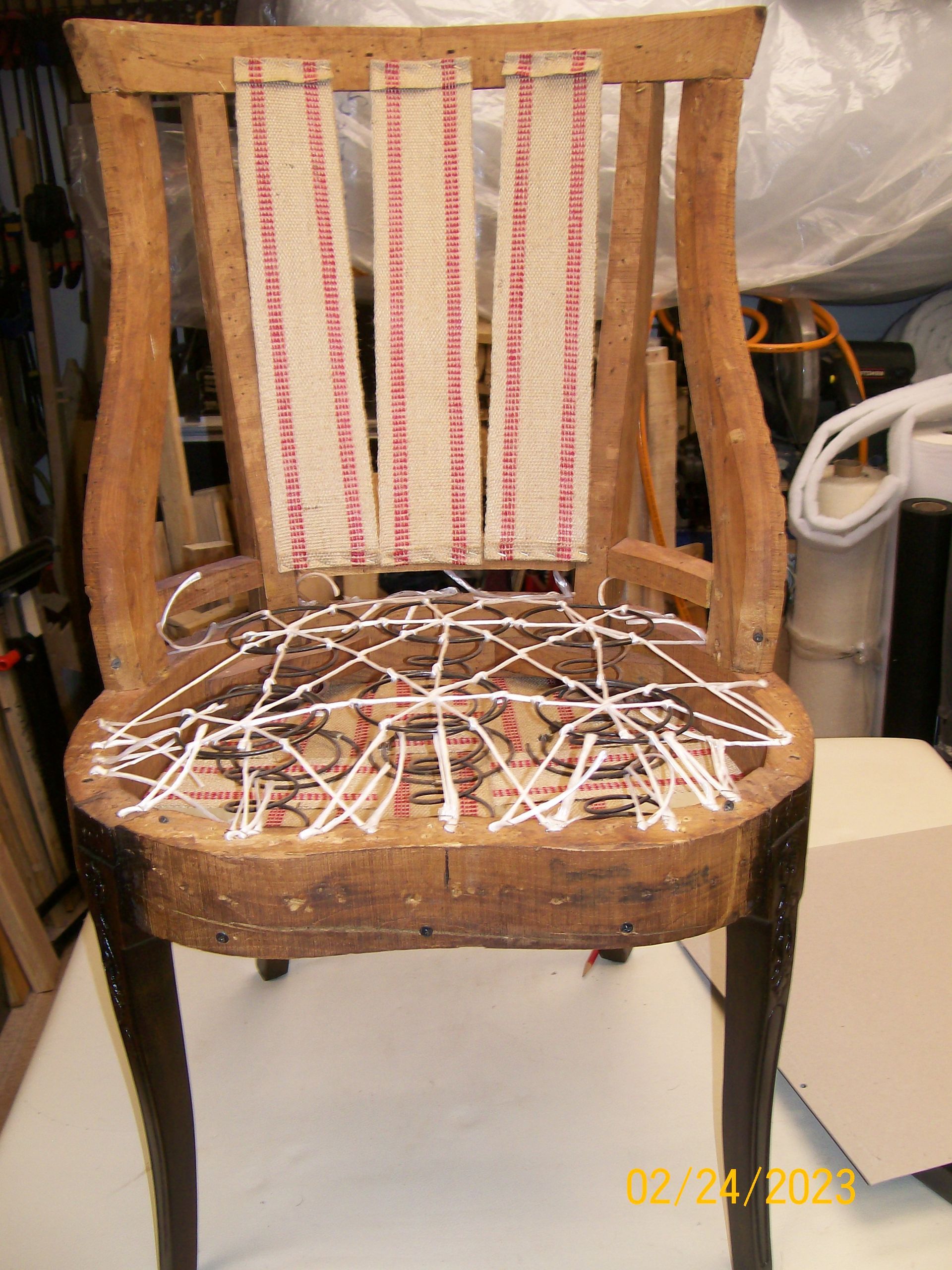A wooden chair with a striped fabric on the back