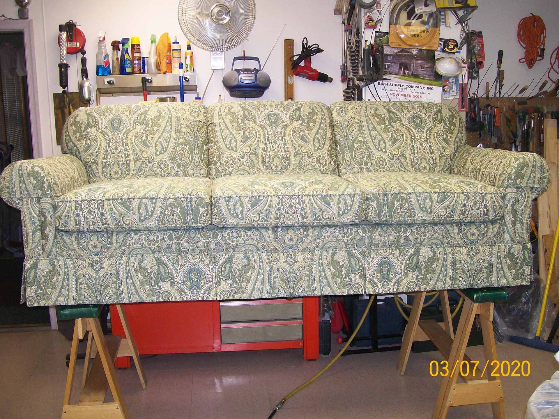 A couch is sitting on a wooden stand in a garage.