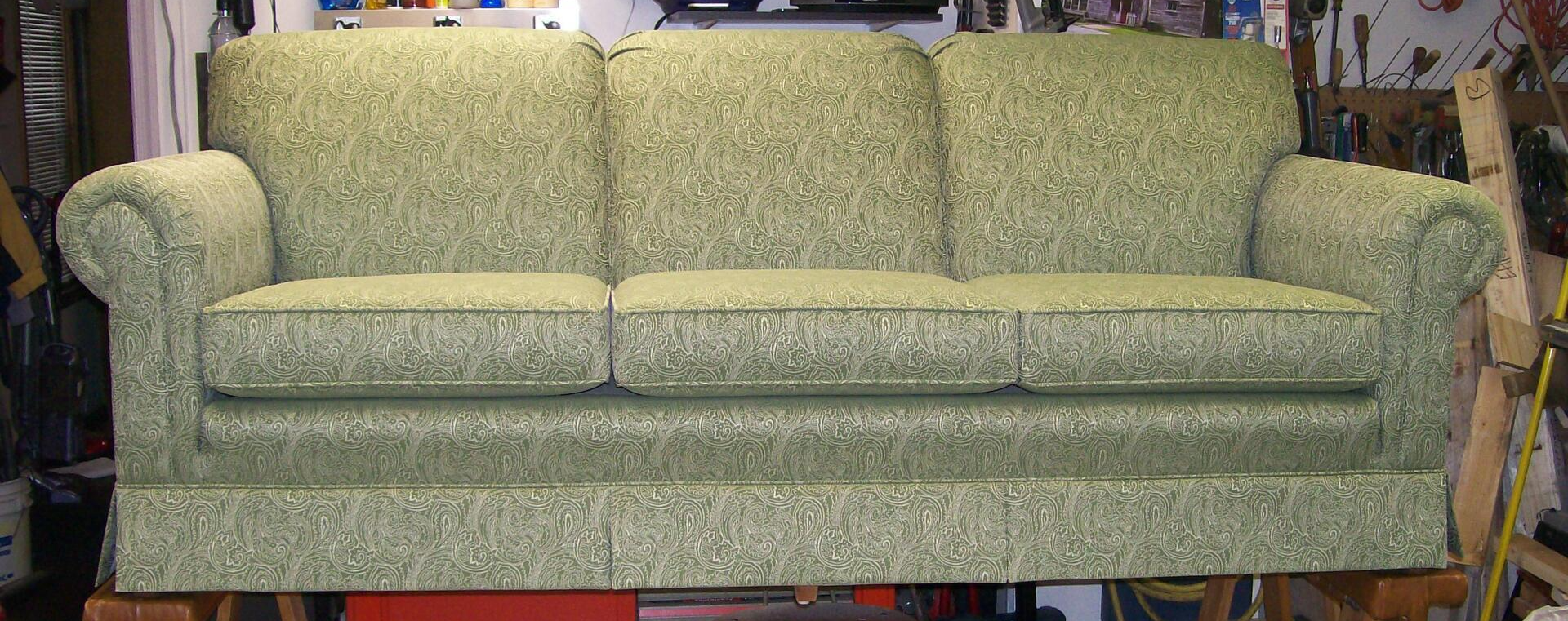 A green couch is sitting on a wooden table in a room.