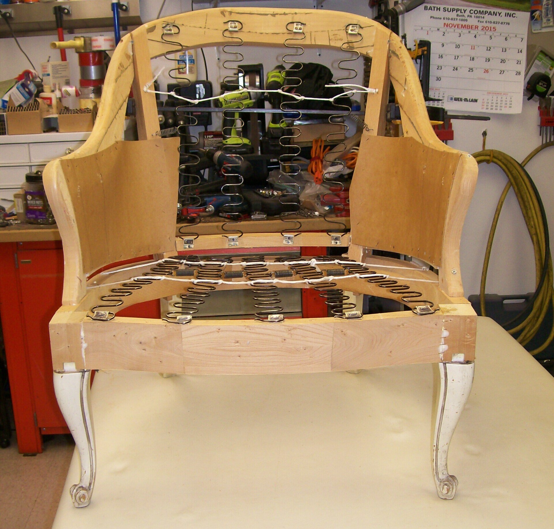 A chair frame is sitting on a table in front of a calendar