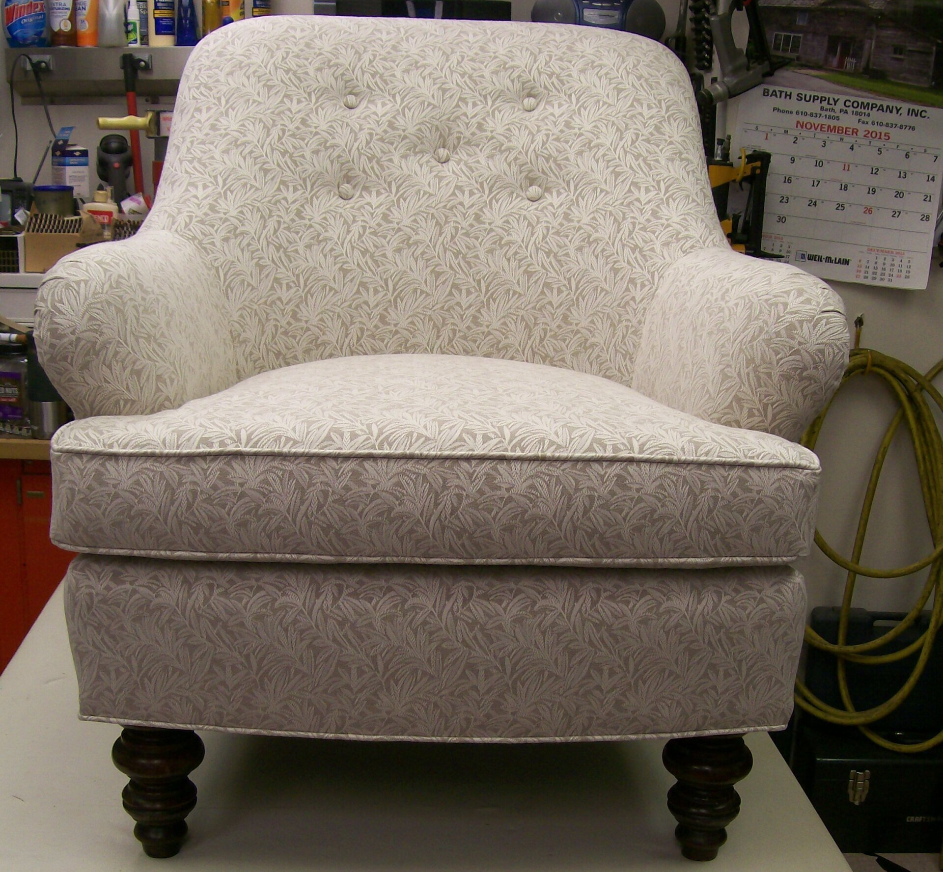 A white chair is sitting on a table with a calendar on the wall behind it