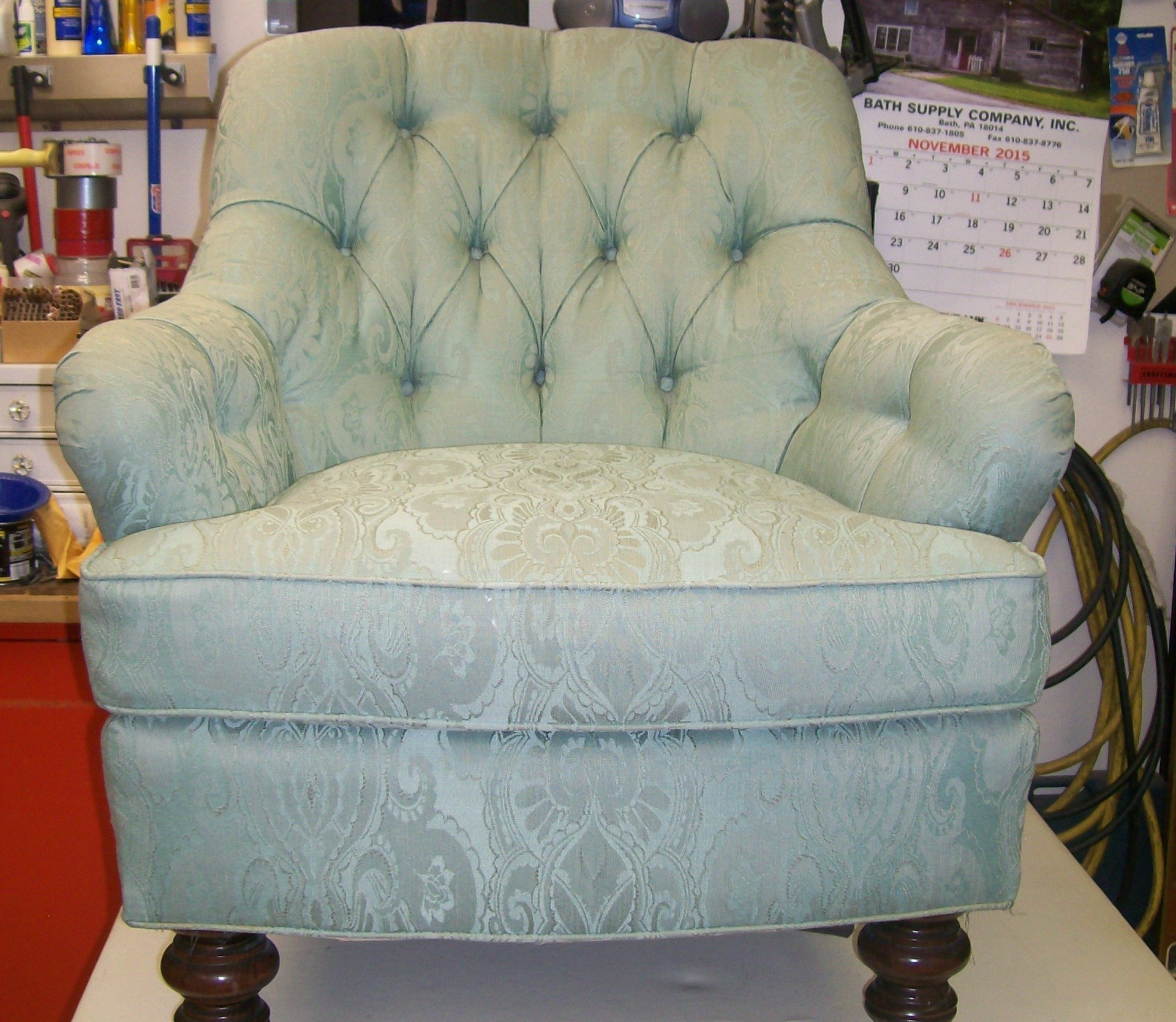 A chair with a calendar on the wall behind it