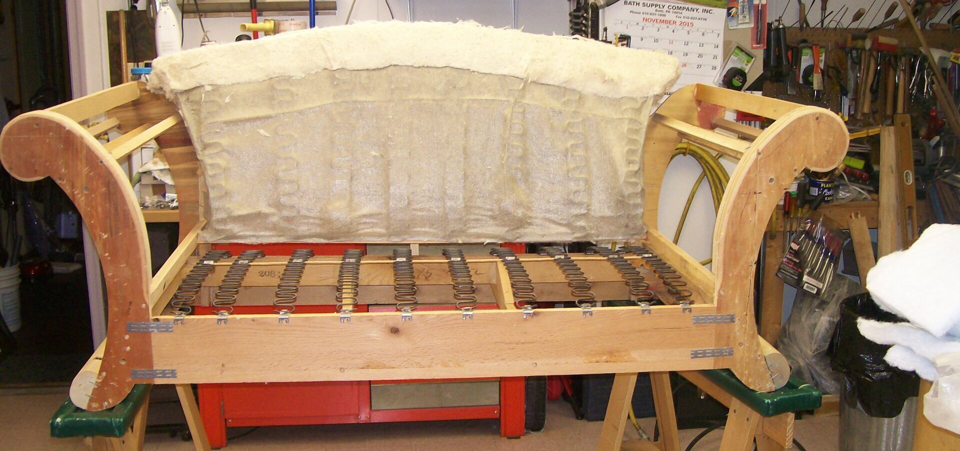A wooden couch is being built in a workshop