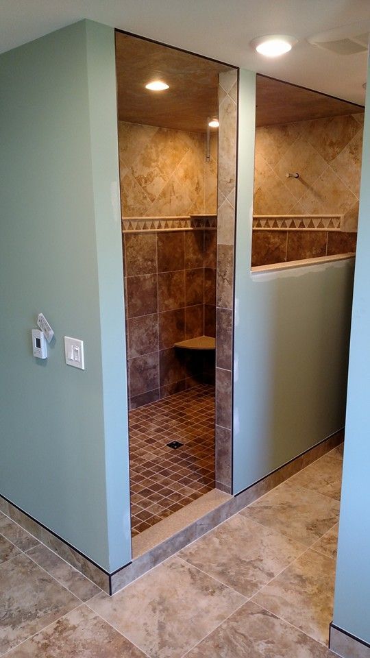 Accessible shower with tile walls, floor, and bench. Light blue and beige walls.