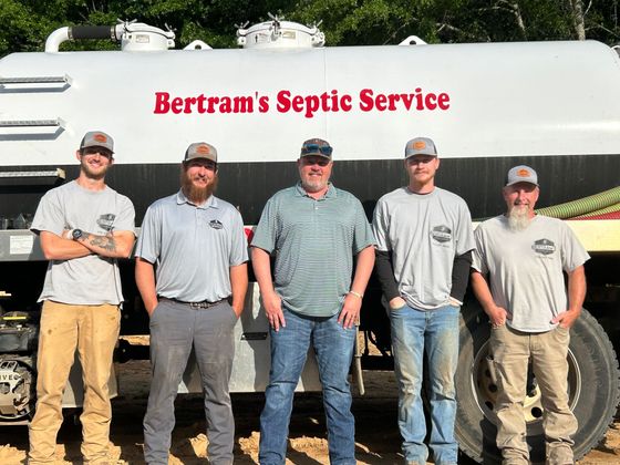 A group of men standing in front of a septic service truck