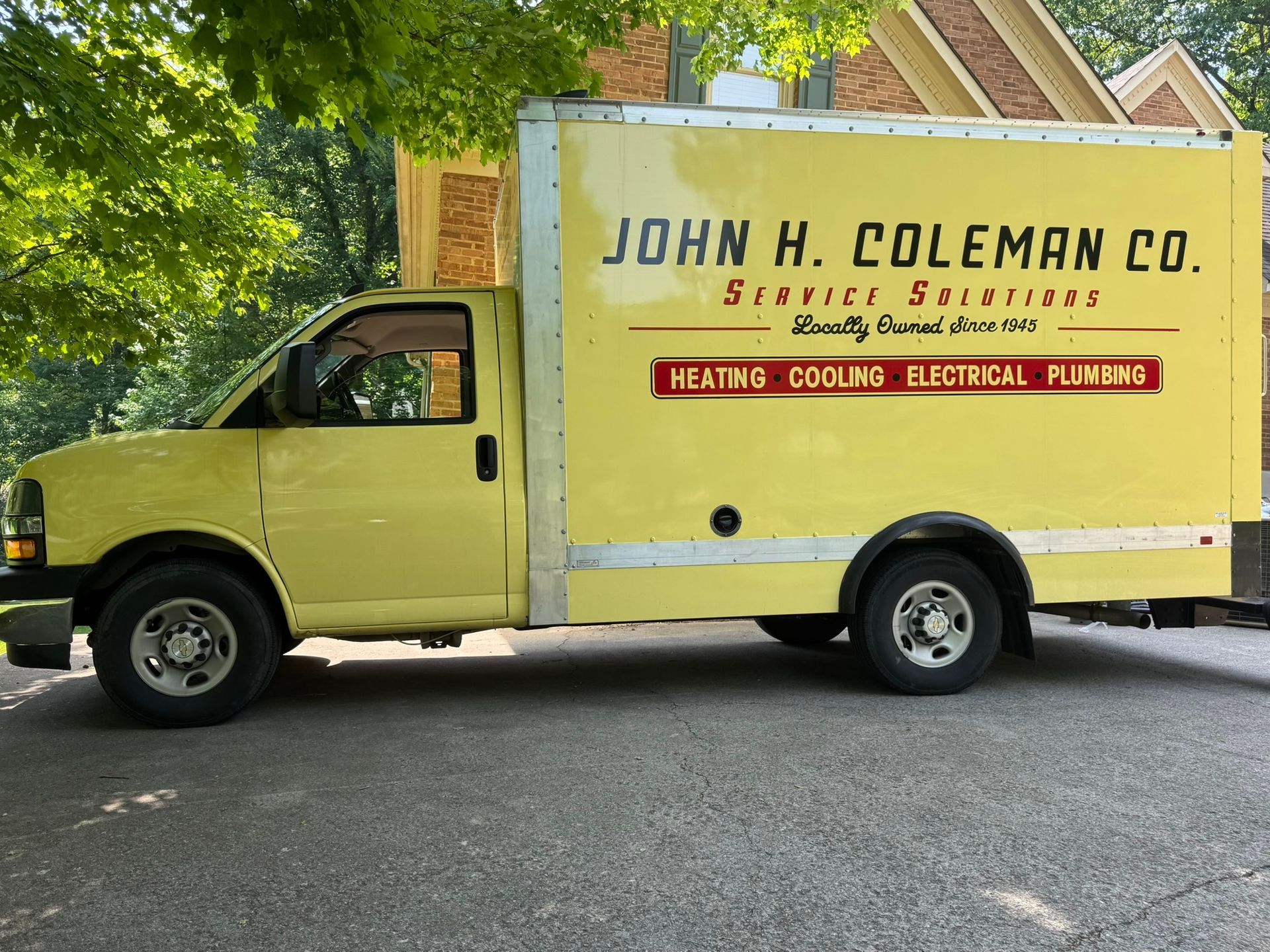 Yellow van parked in front of a brick house with dark green shutters. Man near the entrance.