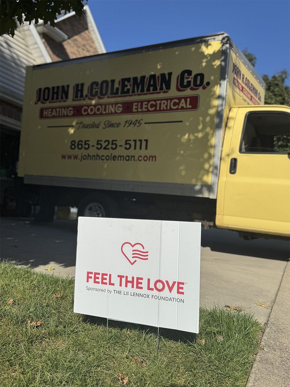 Yellow John H. Coleman Co. truck with sign in front on grass: 