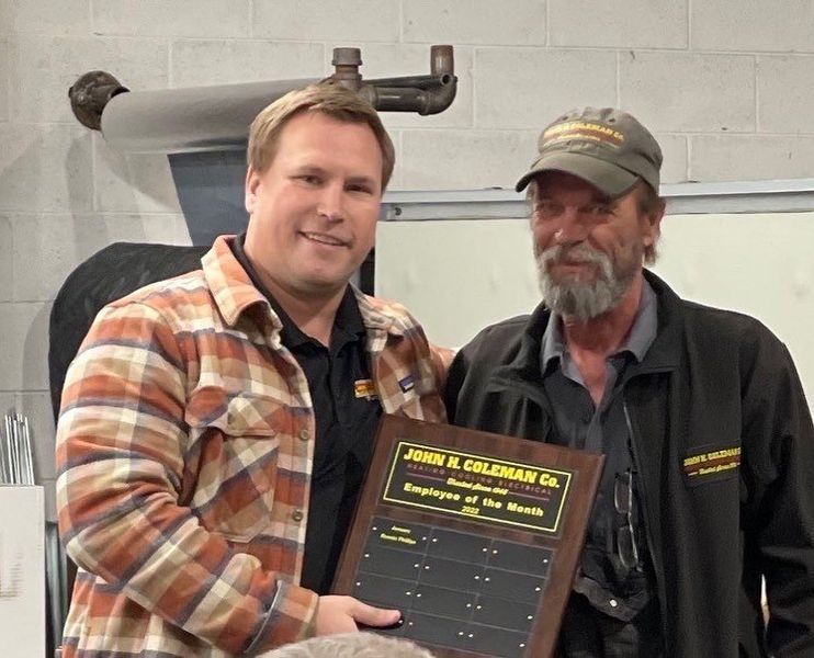 Man presents plaque to another man, both smiling. The plaque reads 