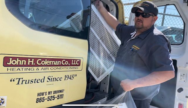 HVAC technician holding an air filter near a van with 