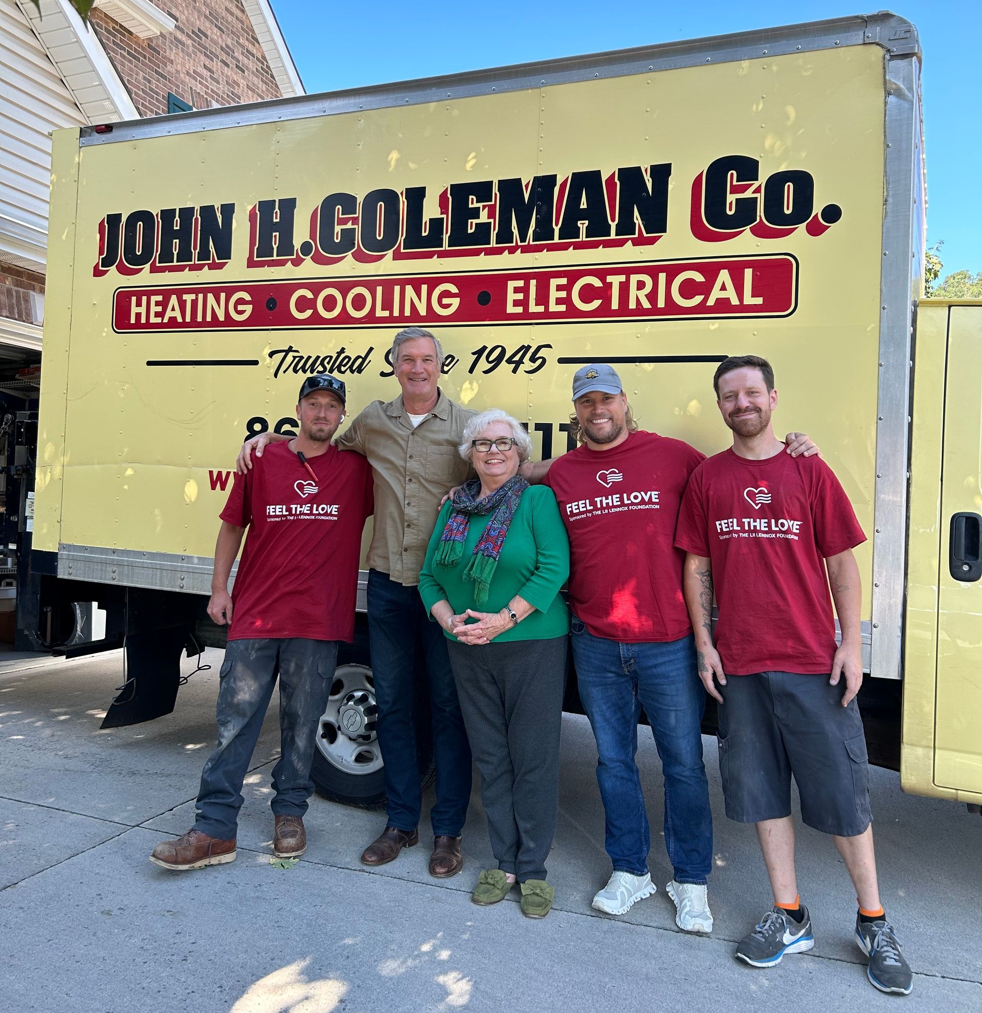 Five people standing in front of a yellow John H. Coleman Co. truck.