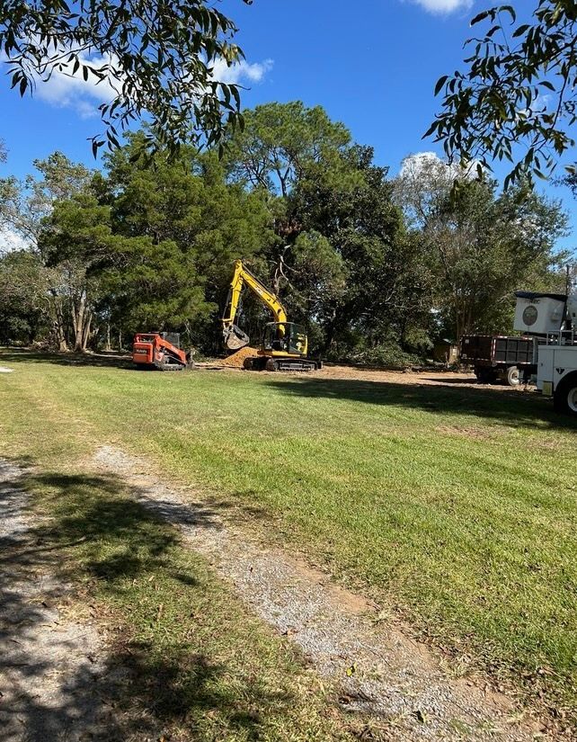 A large yellow excavator is sitting in the middle of a grassy field.