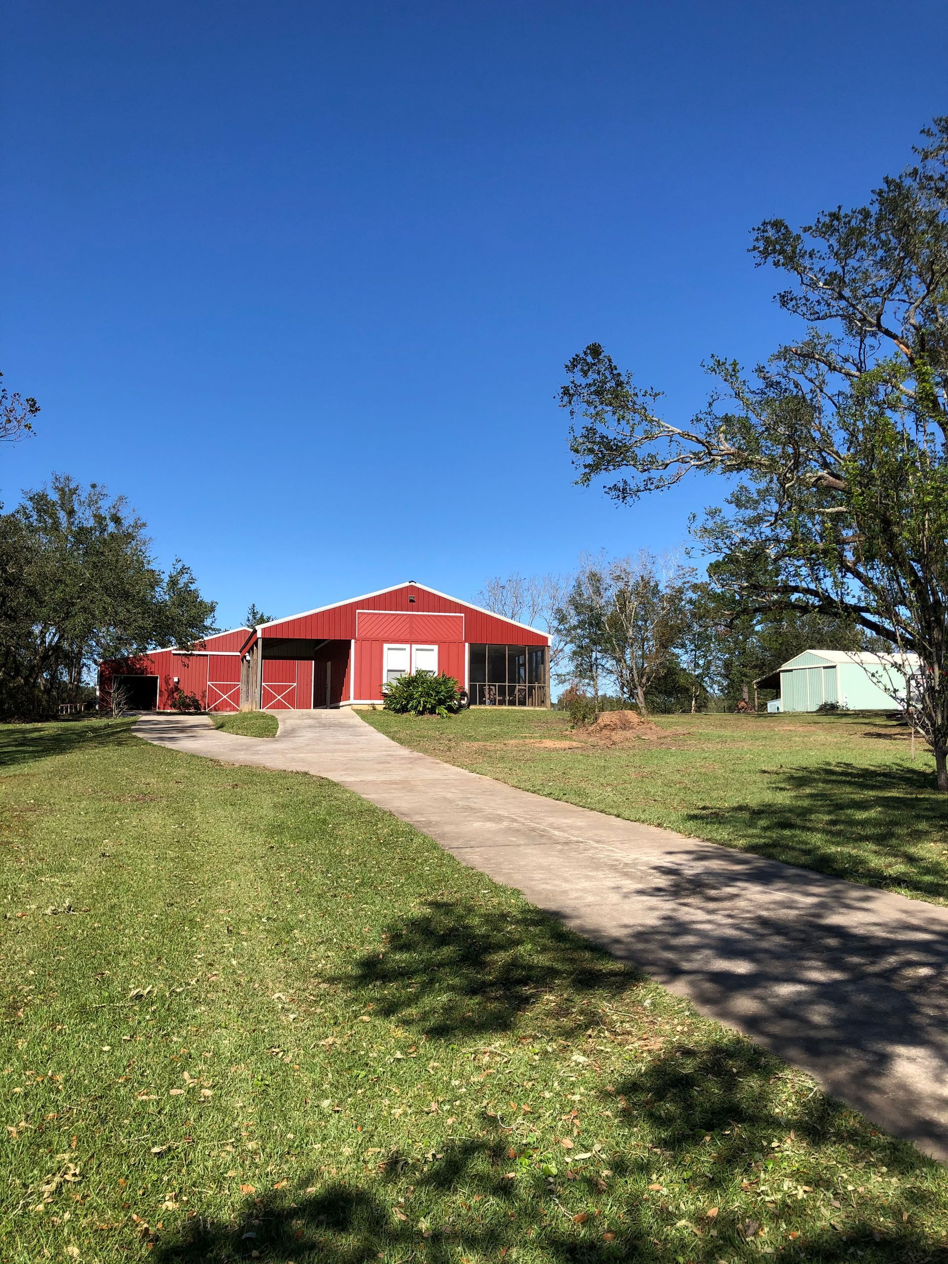 A red barn is sitting in the middle of a grassy field.
