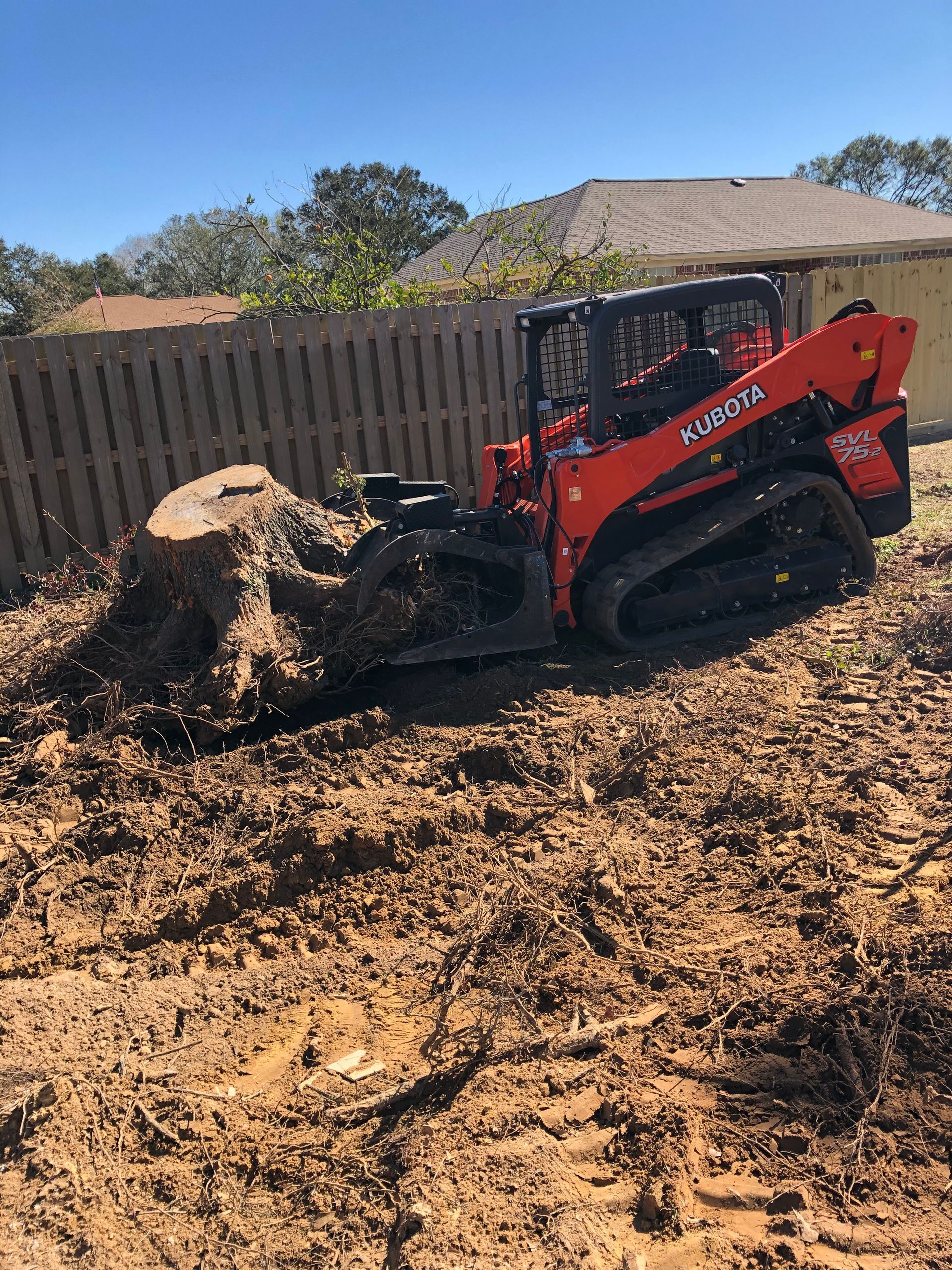A bulldozer is moving a large tree stump in the dirt.