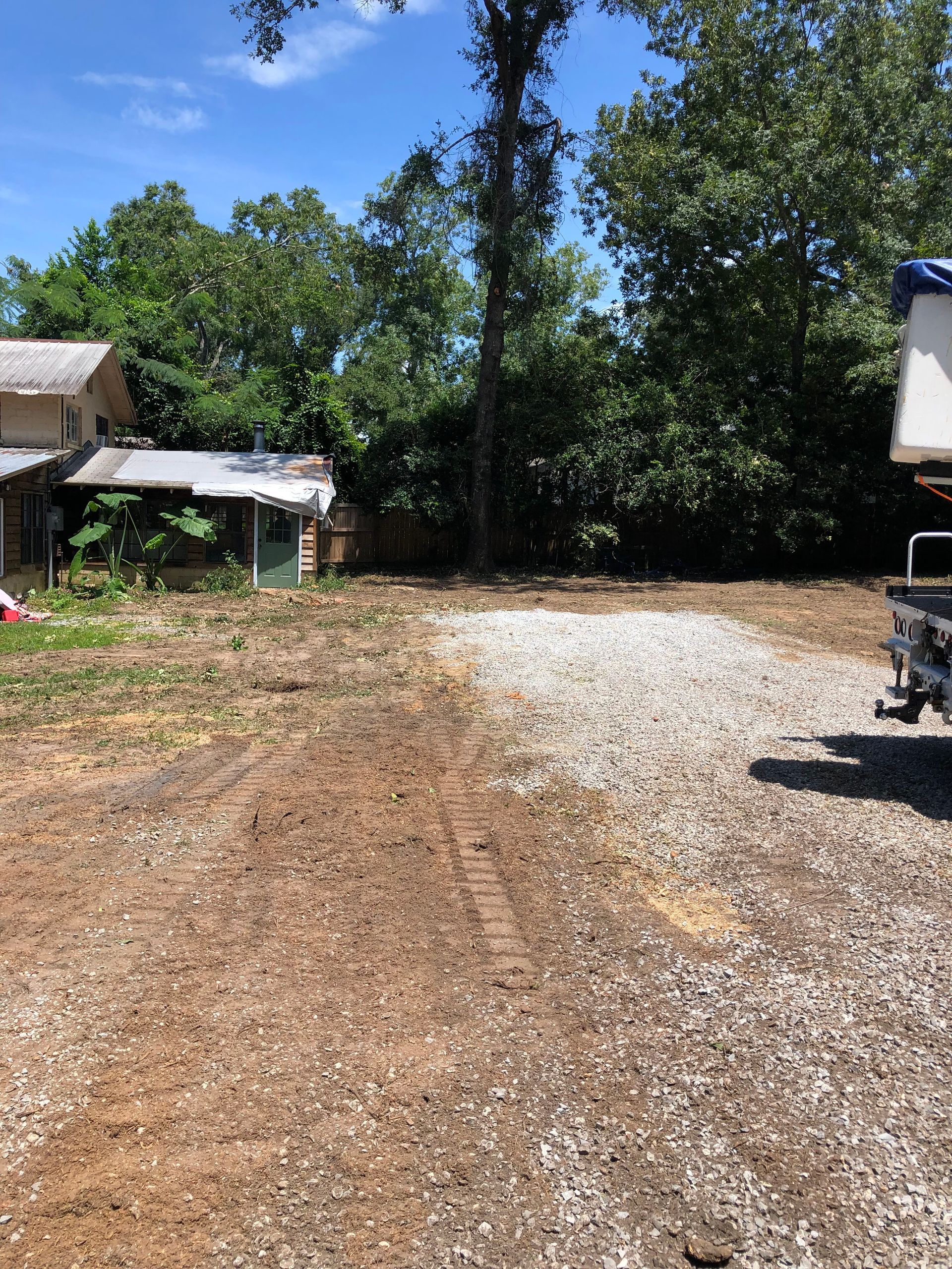A truck is parked in a gravel lot in front of a house.