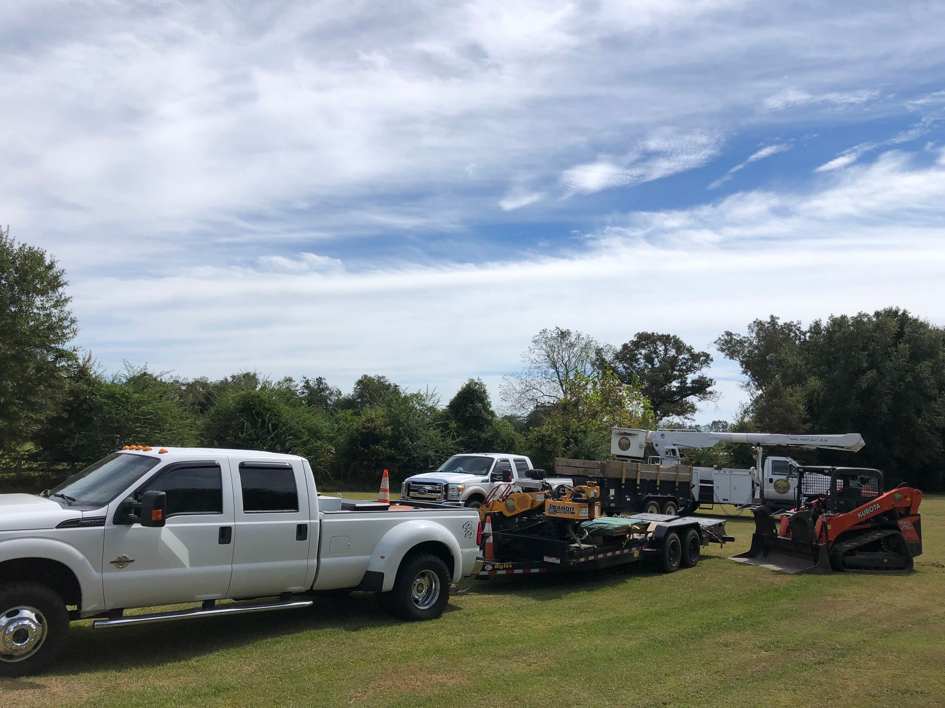 A white truck with a trailer attached to it is parked in a grassy field.