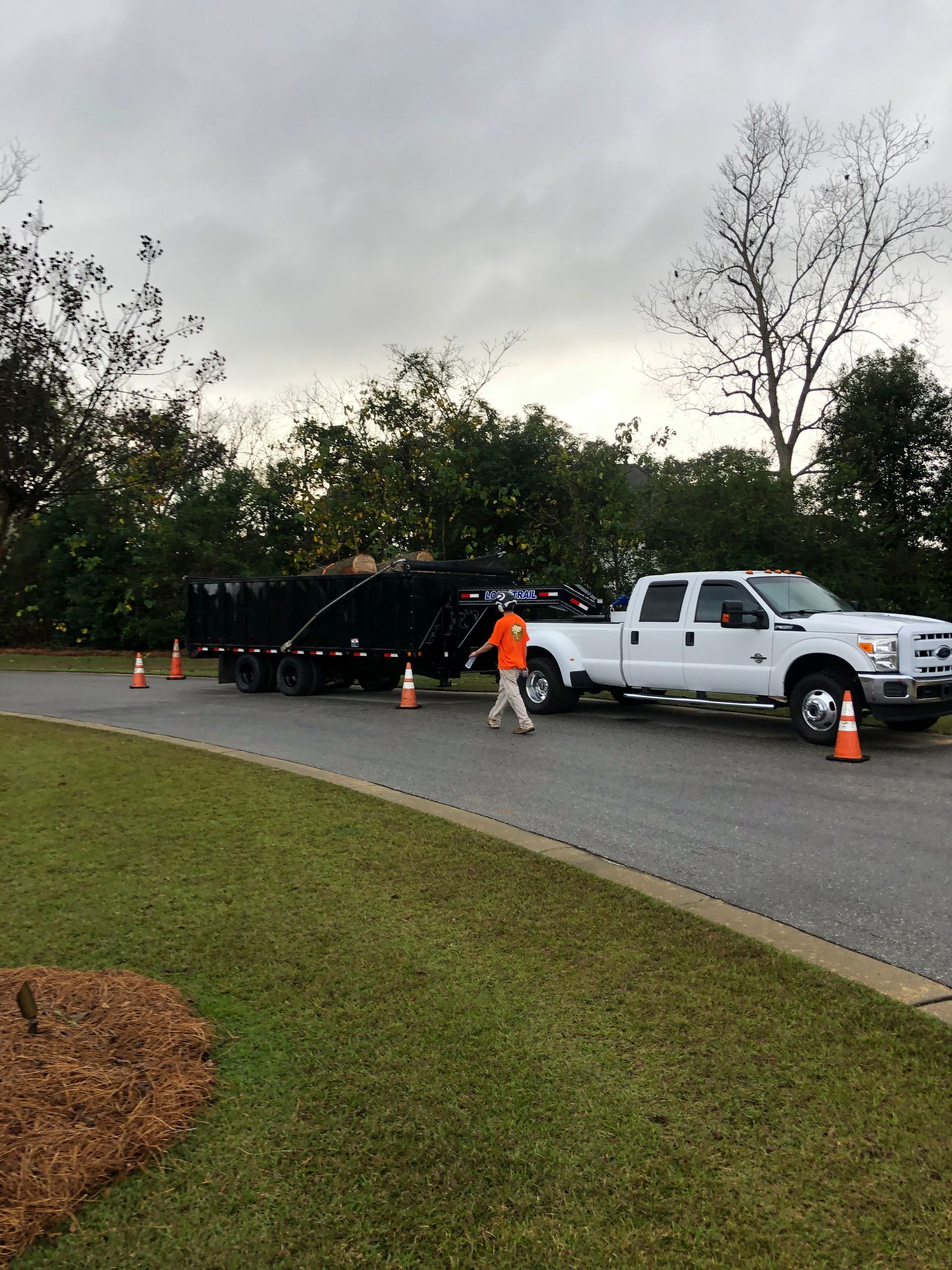 A white truck is pulling a black trailer down a road.